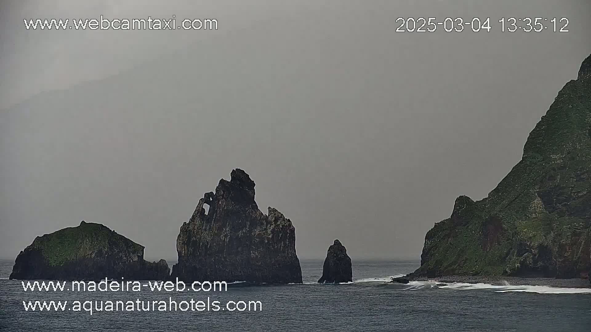 Dark, rocky islands rise from a gray, overcast ocean.