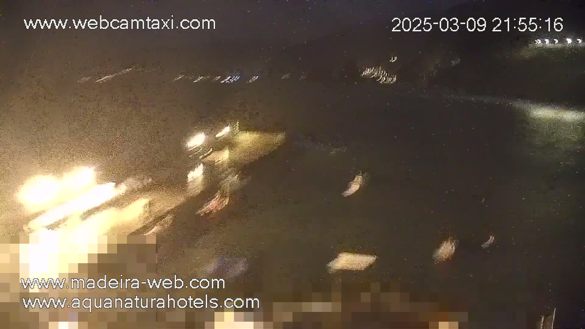 A nighttime, blurry image shows bright lights and what appears to be fireworks in the dark distance.