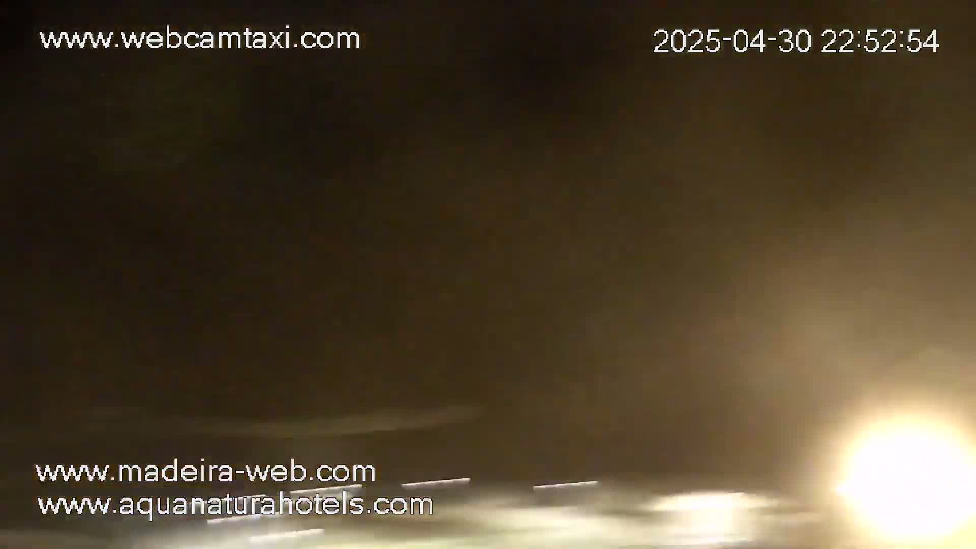 A hazy, dark nighttime scene shows blurred headlights and taillights on a road.