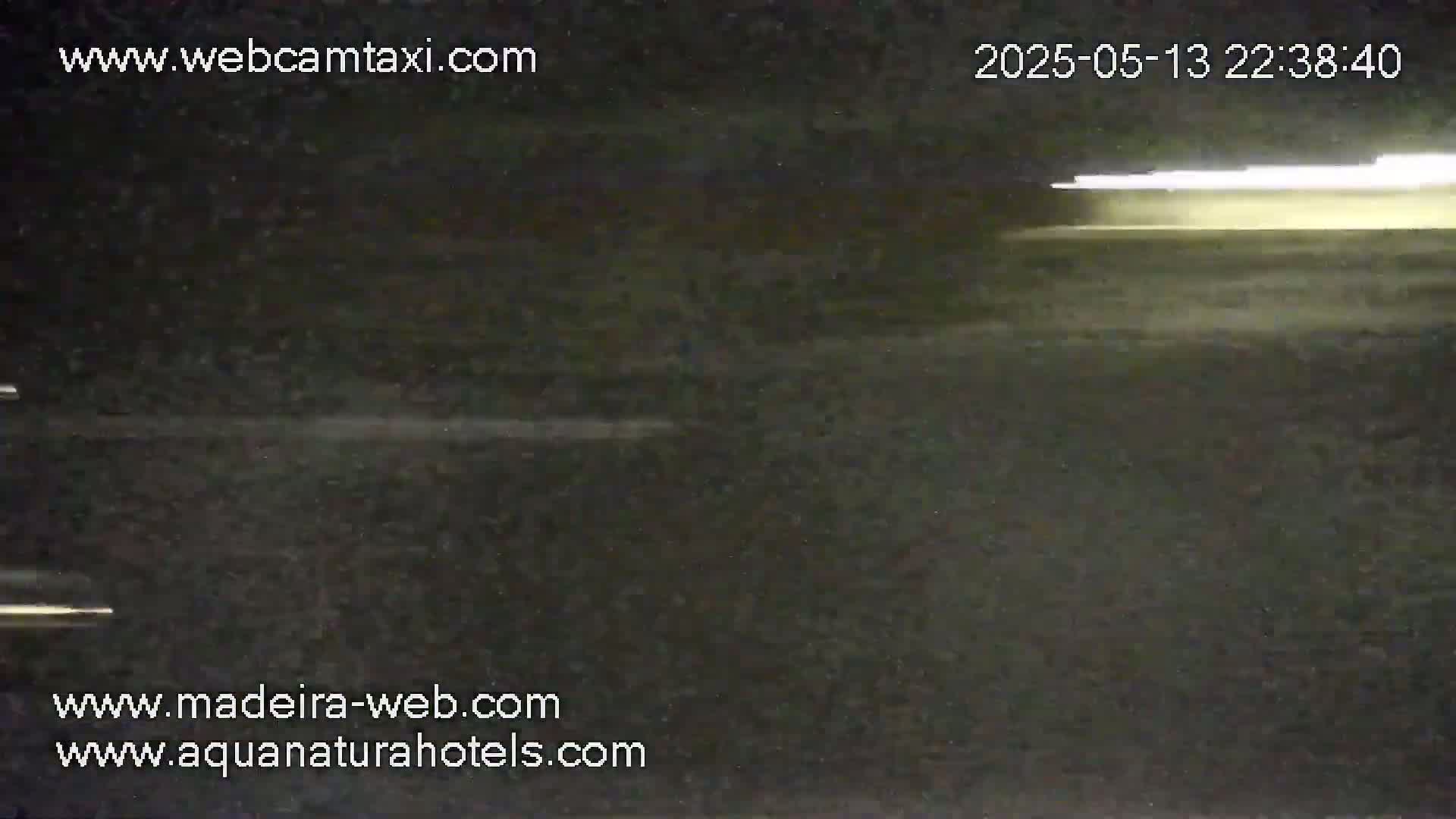 A dark, nighttime scene shows a blurry, light-colored horizontal streak across a dark surface.