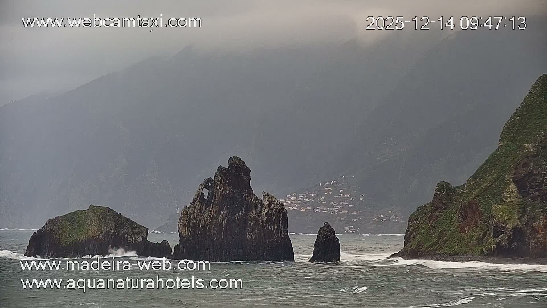 A clear night sky overlooks an outdoor scene brightly decorated with white lights, illuminating a cross-shaped building, a large fountain, and various trees.