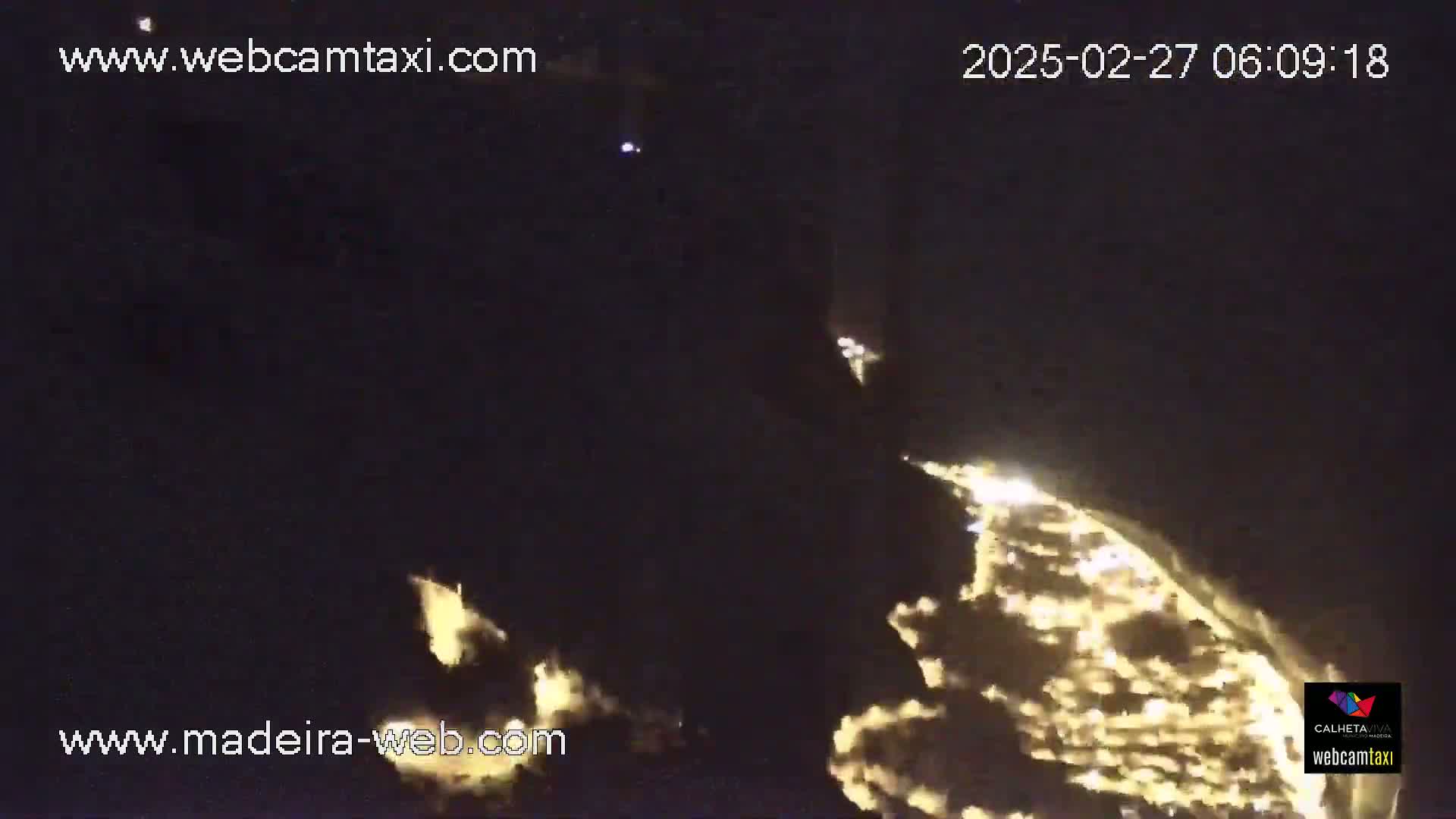 A nighttime long shot shows a glowing, bright expanse of lights on the horizon, possibly city lights or a fire, against a dark sky.