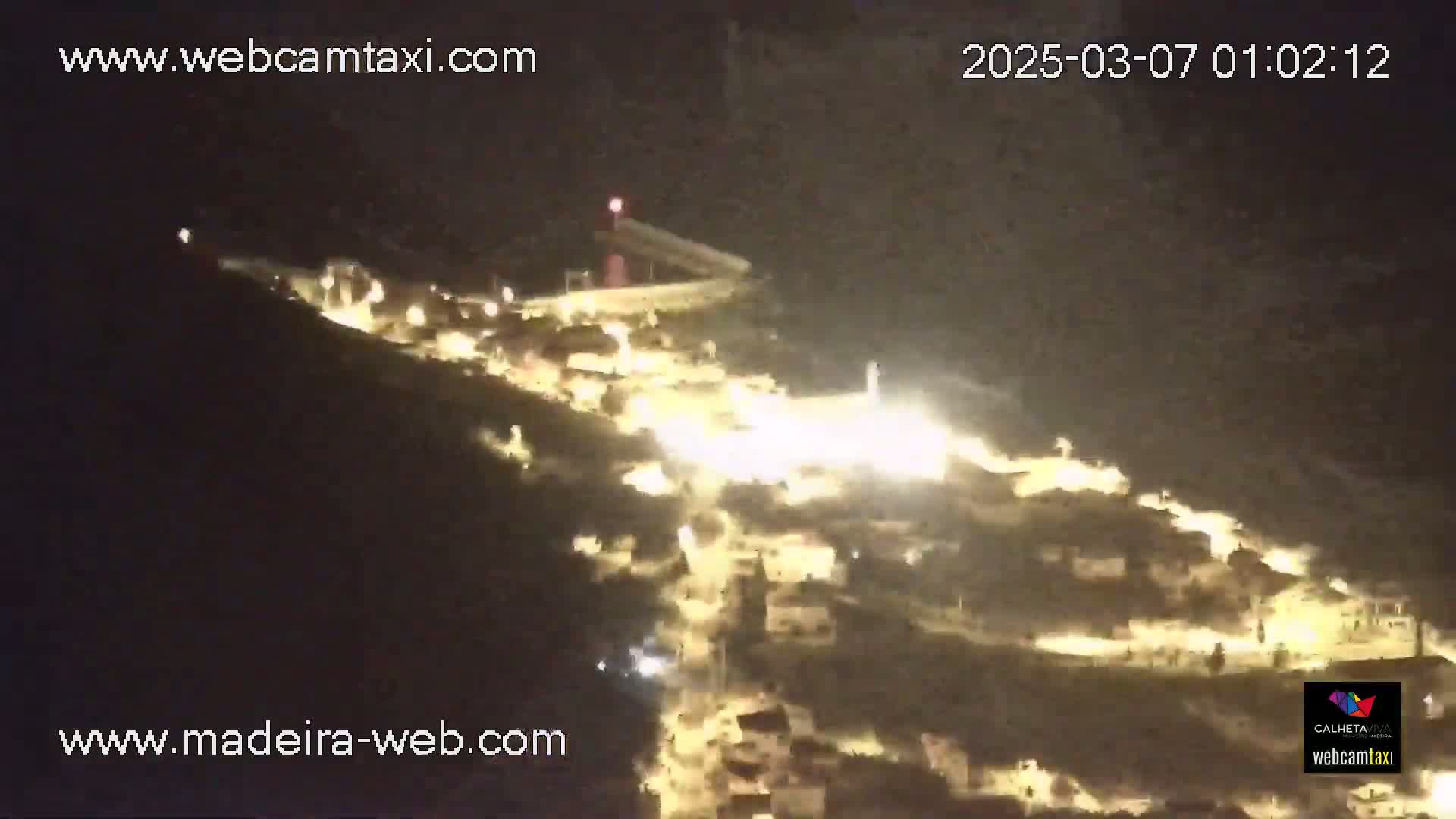 A nighttime, aerial view shows a hillside town illuminated by streetlights.