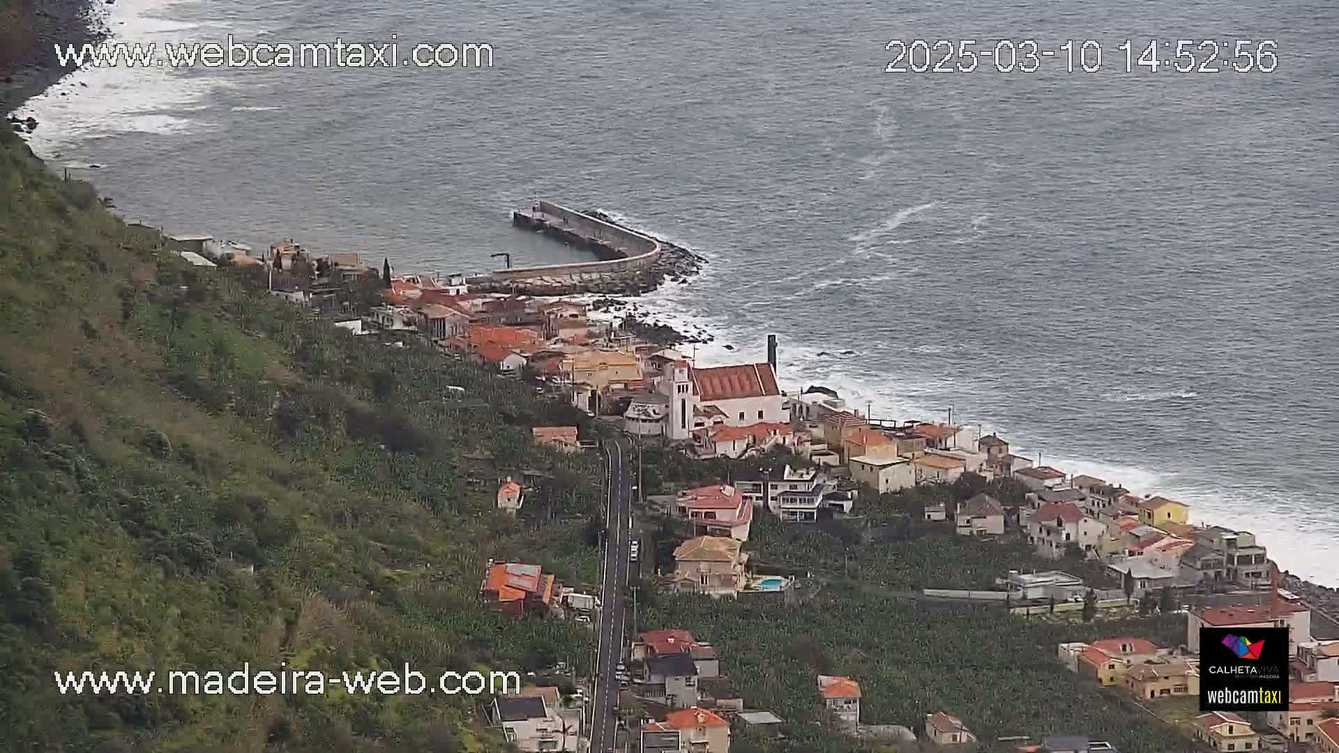 A coastal town with a church nestled on a hillside overlooking a dark, choppy ocean.