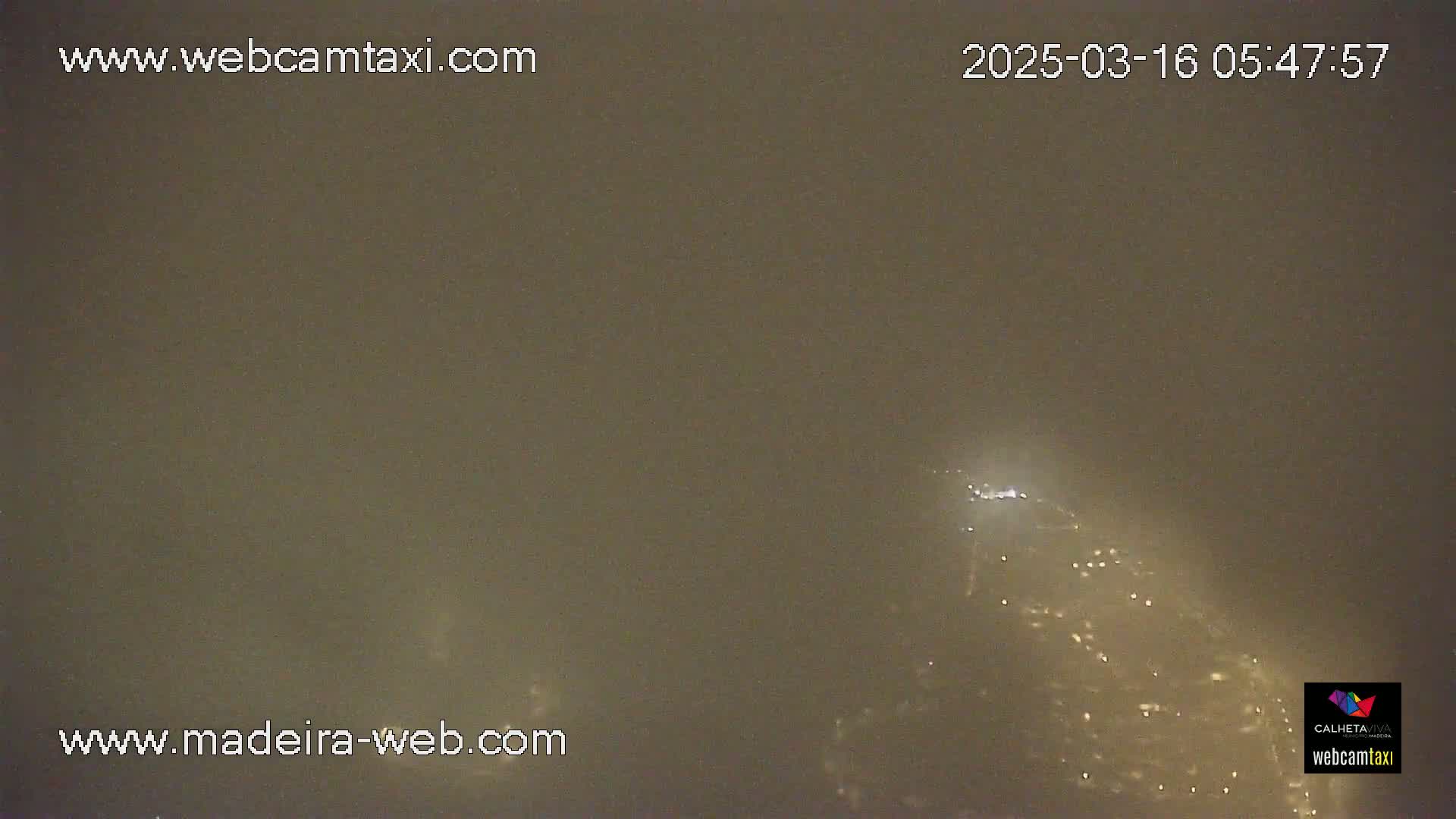 A hazy, nighttime view shows distant city lights below a muted, dark sky.