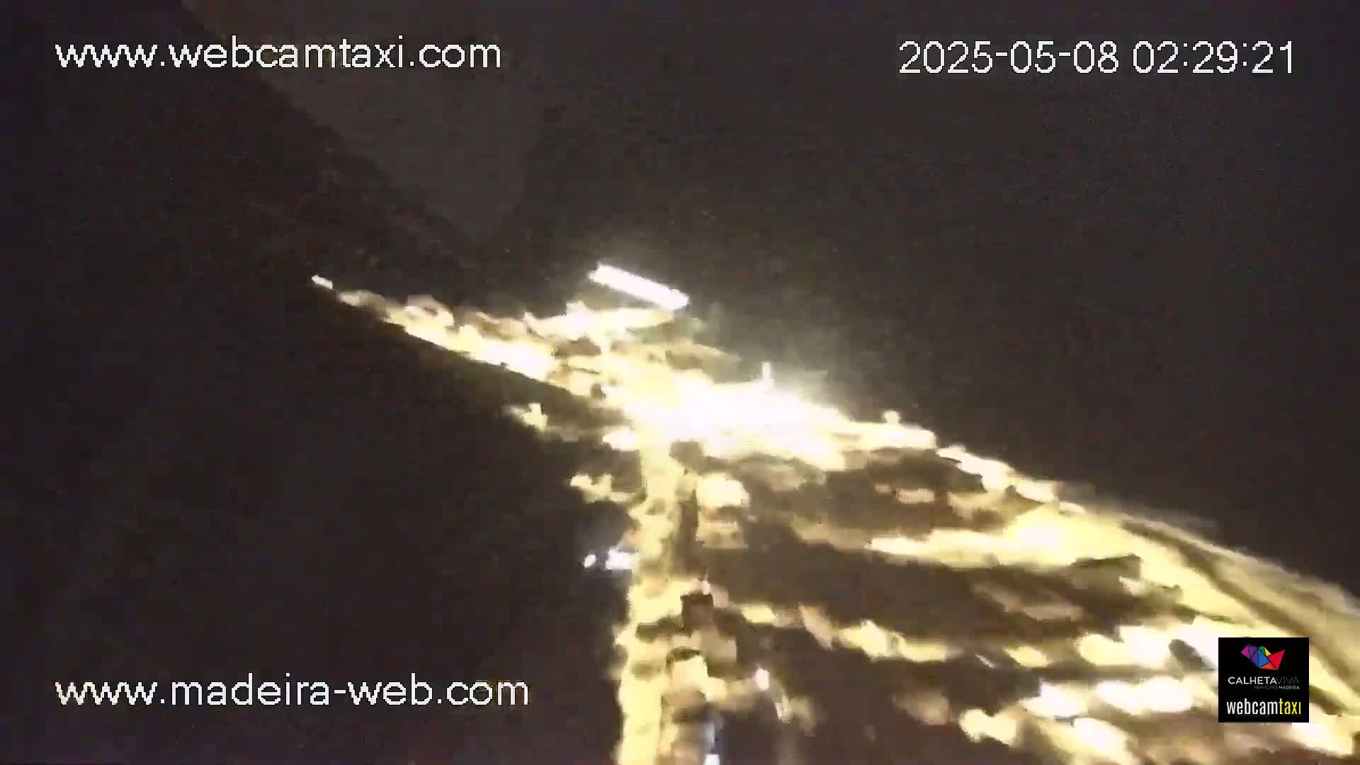A nighttime, blurry view of a bright, winding road or path illuminated by vehicle headlights.