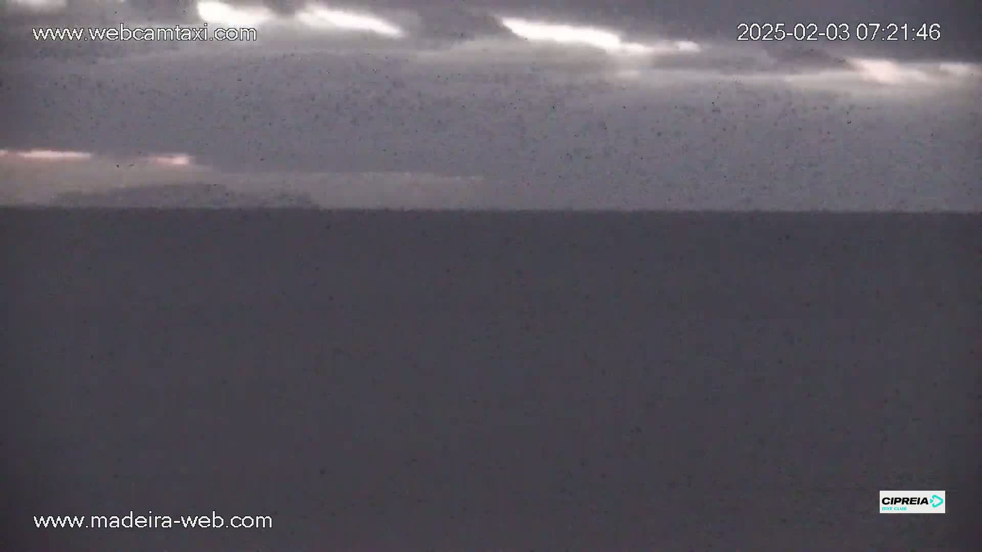 A dark, overcast sky hangs over a calm, gray ocean.