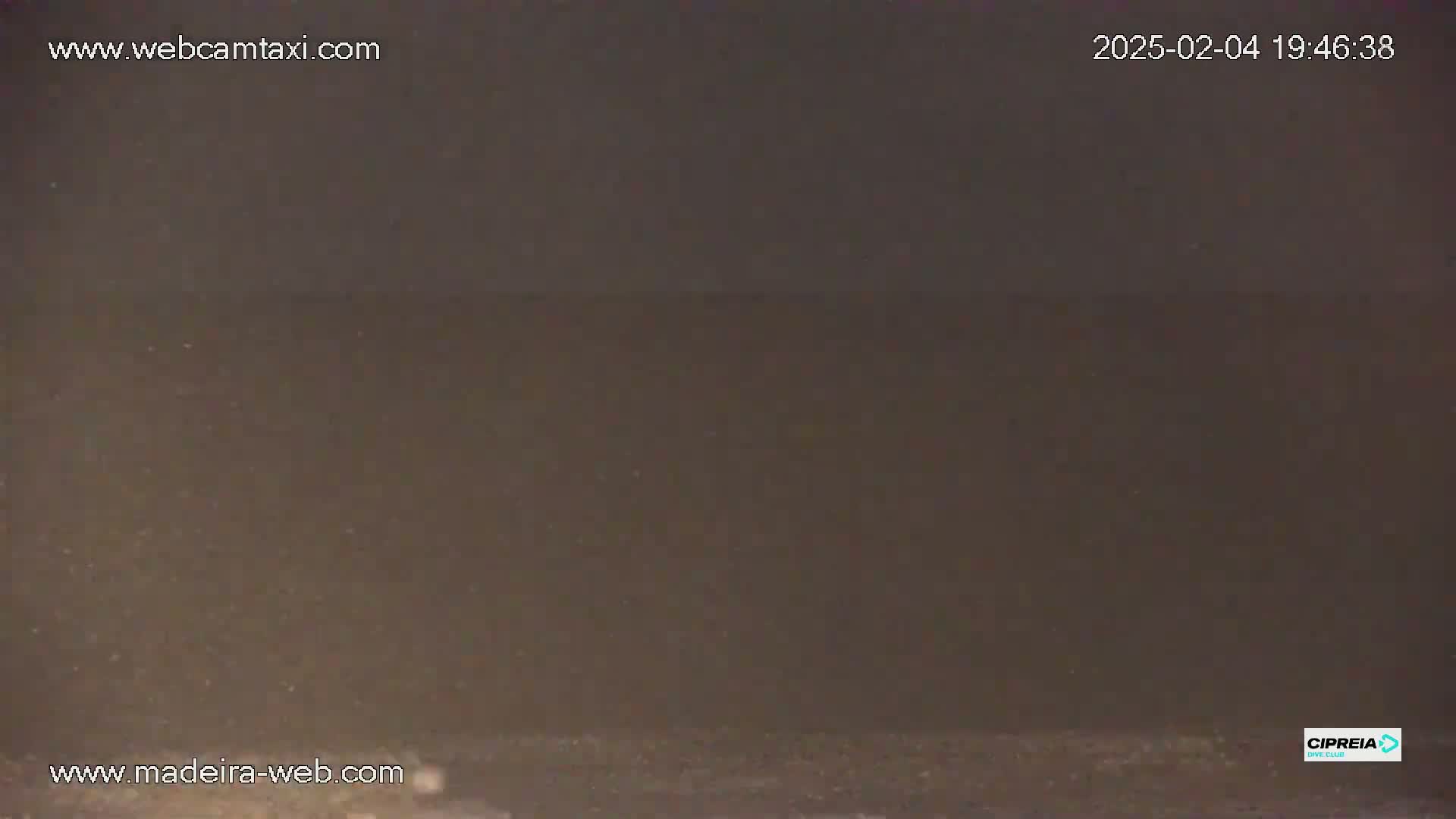 A dark, possibly nighttime, outdoor scene shows a body of water under a hazy or dusty sky.
