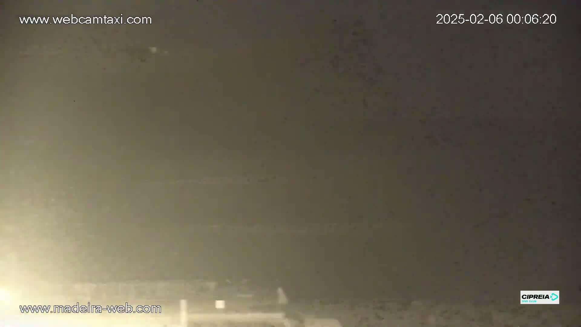 A nighttime, hazy, outdoor scene shows a dimly lit area with low visibility.