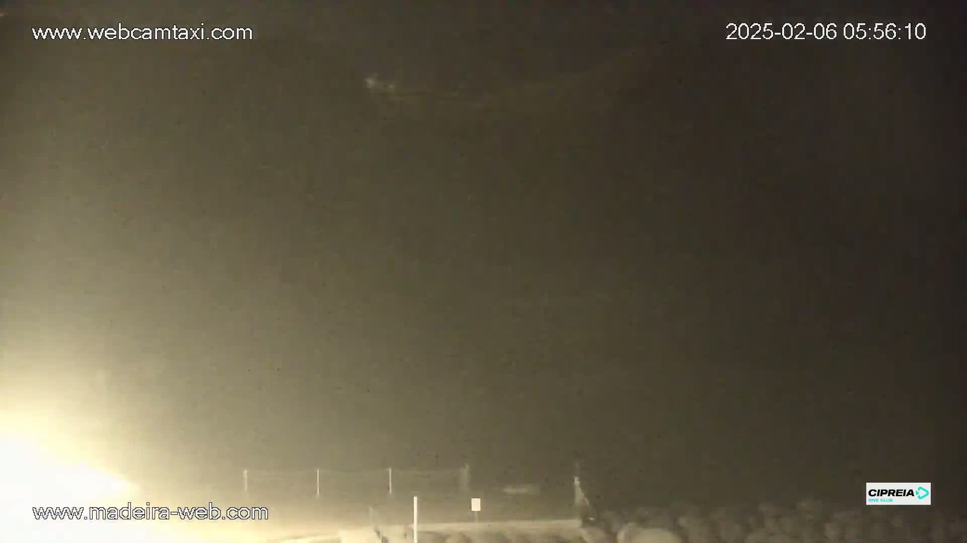 A nighttime, hazy or foggy scene shows a dark area with a few dimly lit objects in the bottom right corner.