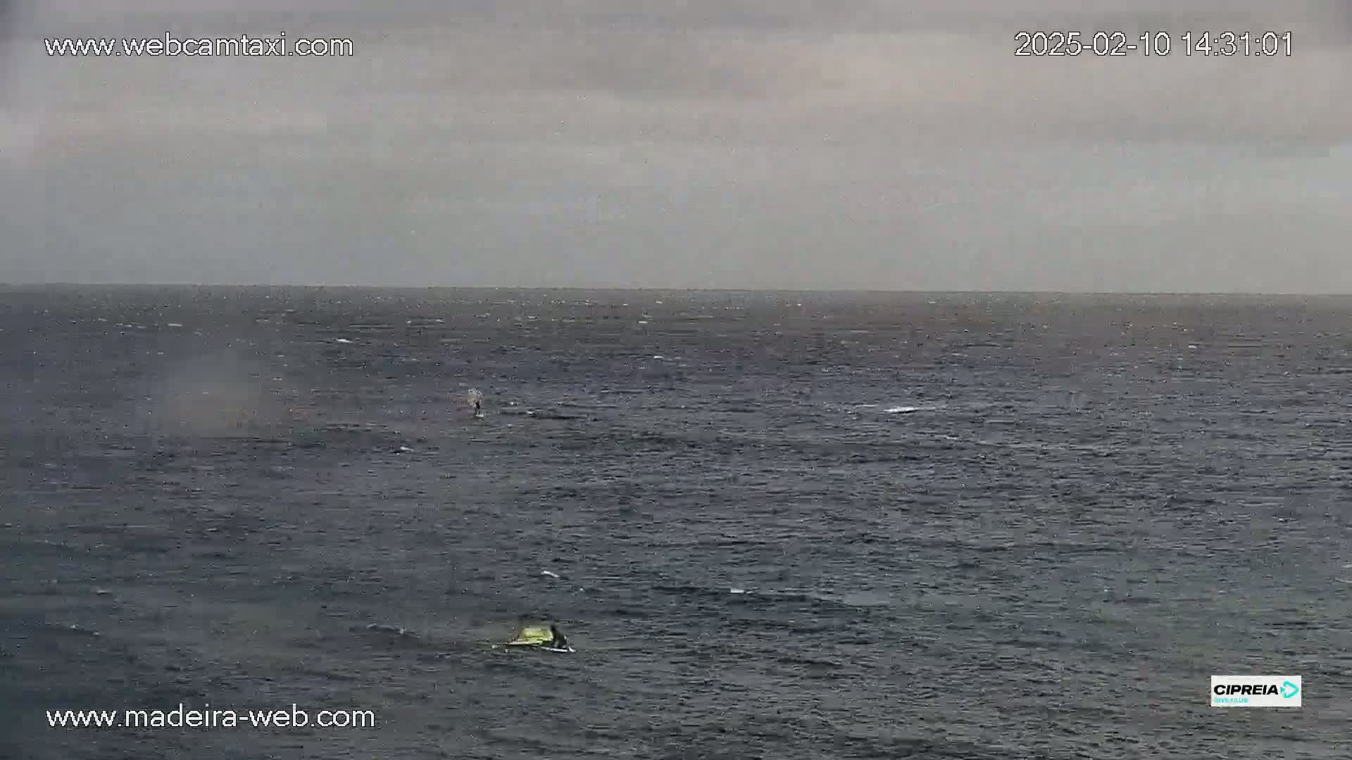 Two small watercraft are visible on a dark, somewhat choppy sea under an overcast sky.