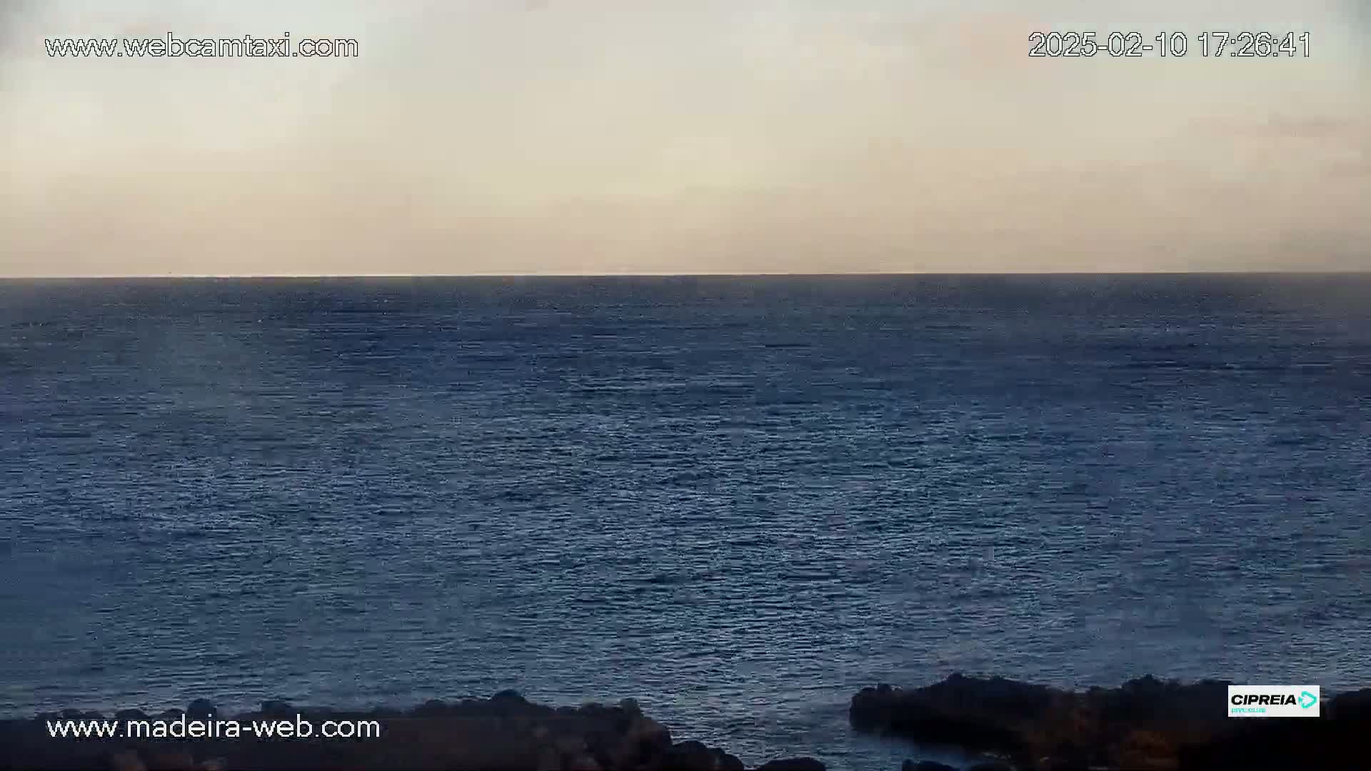 A calm, dark blue ocean stretches to a pale, hazy horizon under a muted sky.