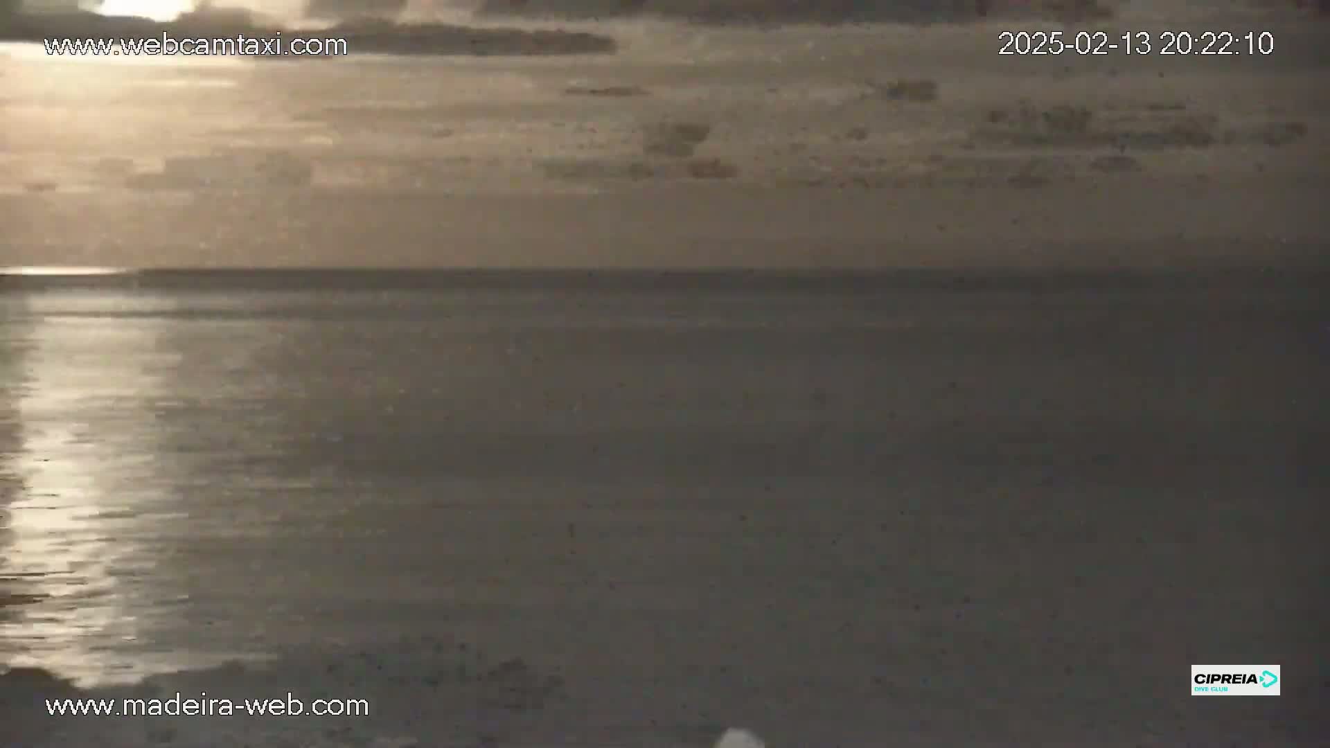 A calm, dark ocean is visible under a cloudy, dusky sky.