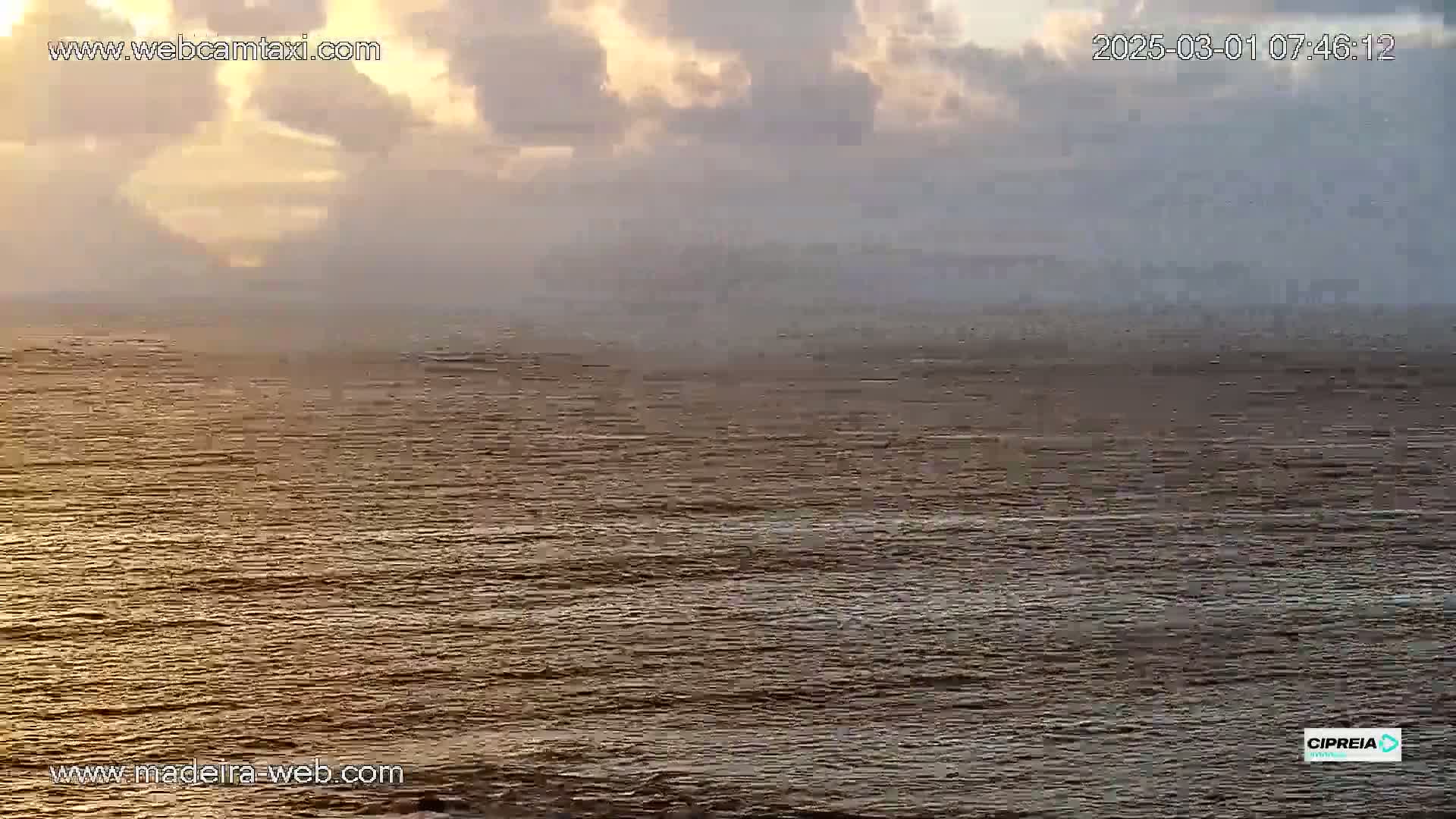 A calm ocean under a cloudy, sunrise sky.