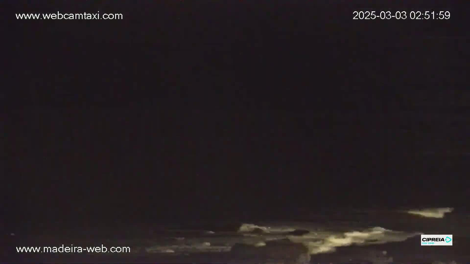 A dark nighttime scene shows choppy waves at the water's edge.