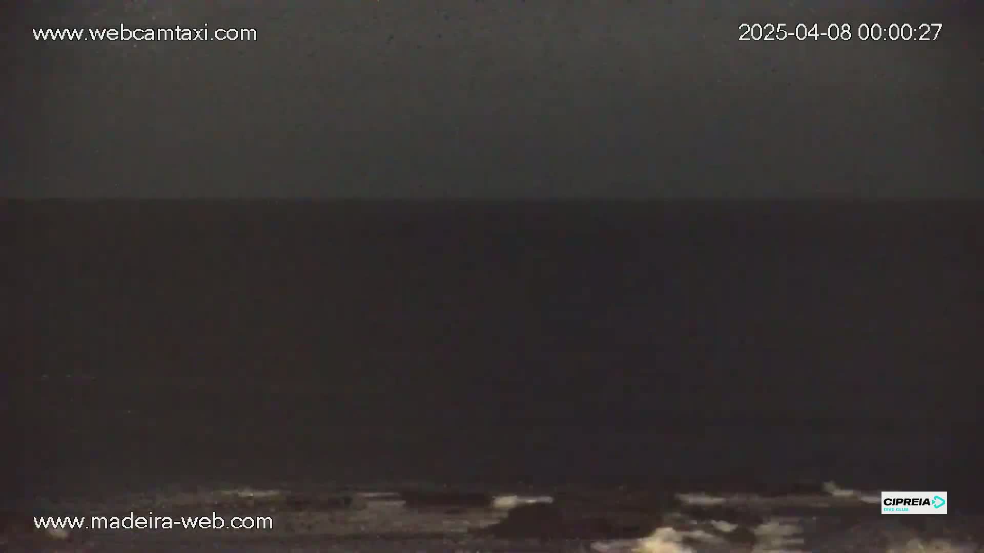 A dark, nighttime ocean scene shows a mostly calm sea with slight wave action at the bottom of the frame.