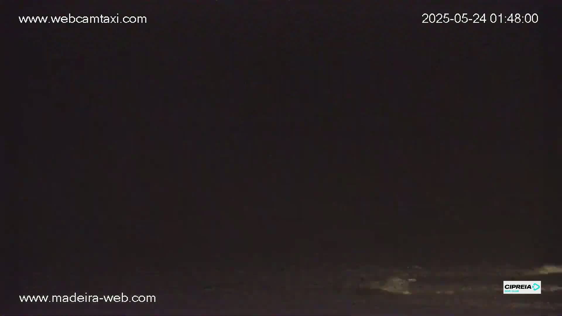 A dark, nighttime scene shows a mostly black ground with a few small, bright spots visible in the lower right.