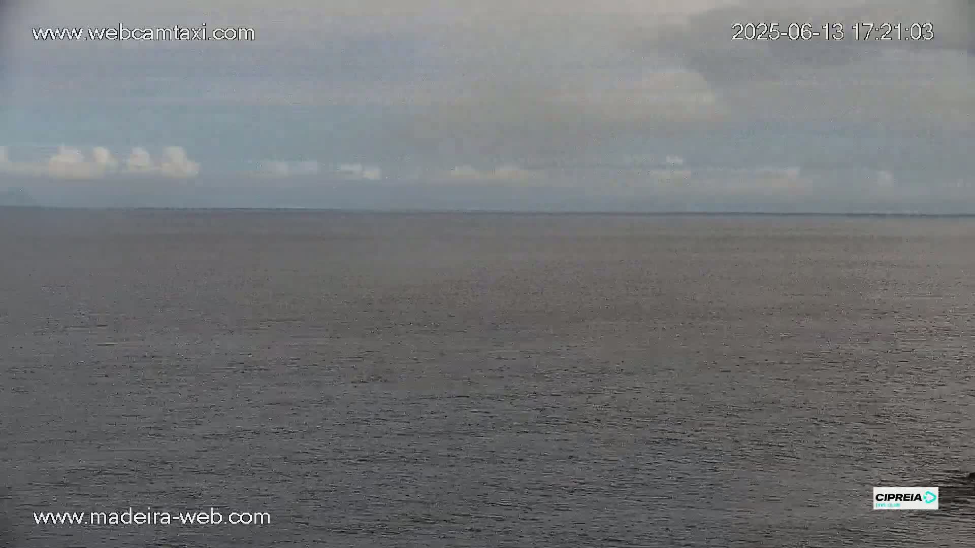 A calm, gray ocean is visible under an overcast sky with a few small, white clouds.