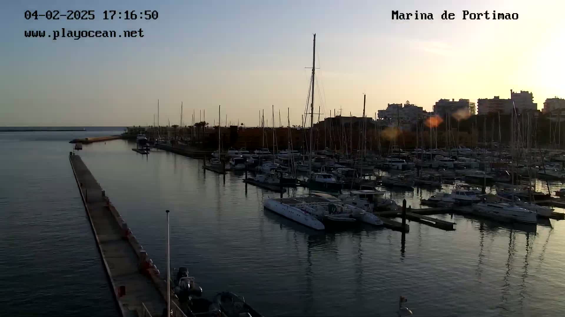 A marina filled with numerous boats and yachts at sunset under a clear sky.