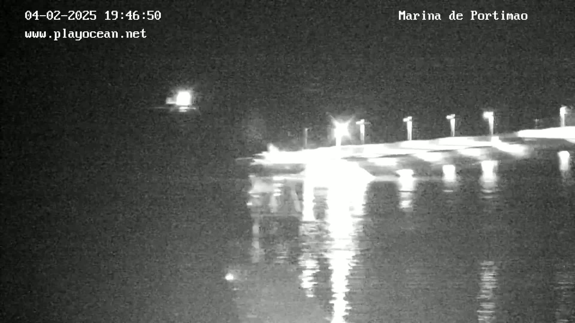 A nighttime view of a marina with lights reflecting on calm water.