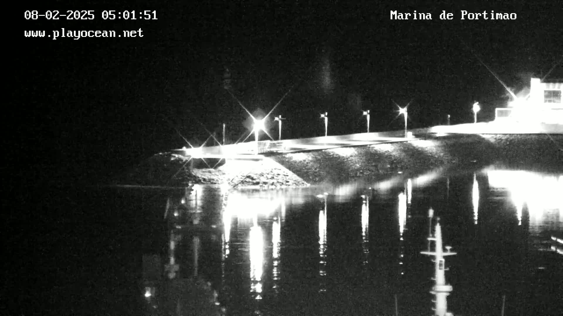 A nighttime, low-light view of a marina with lights reflecting on calm water.