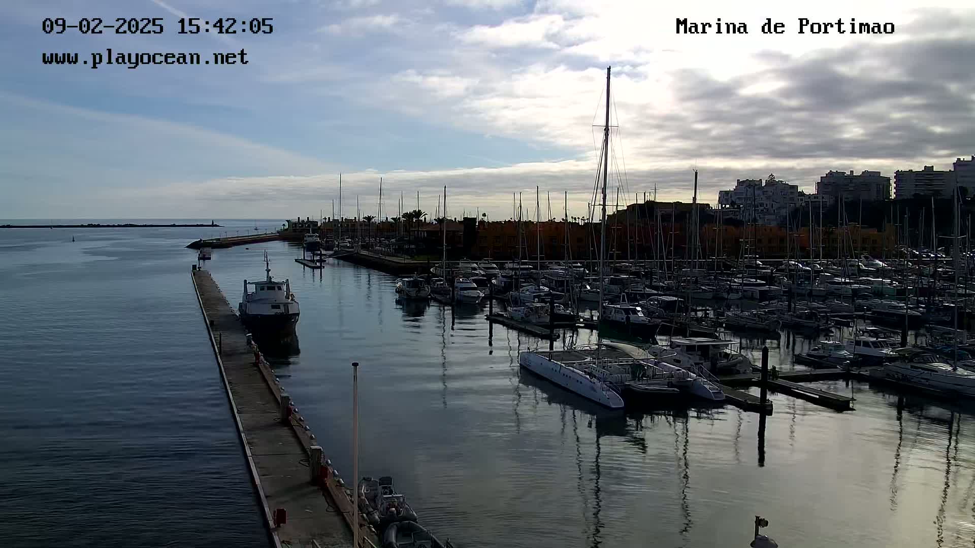 A marina filled with numerous boats and yachts under a partly cloudy sky.
