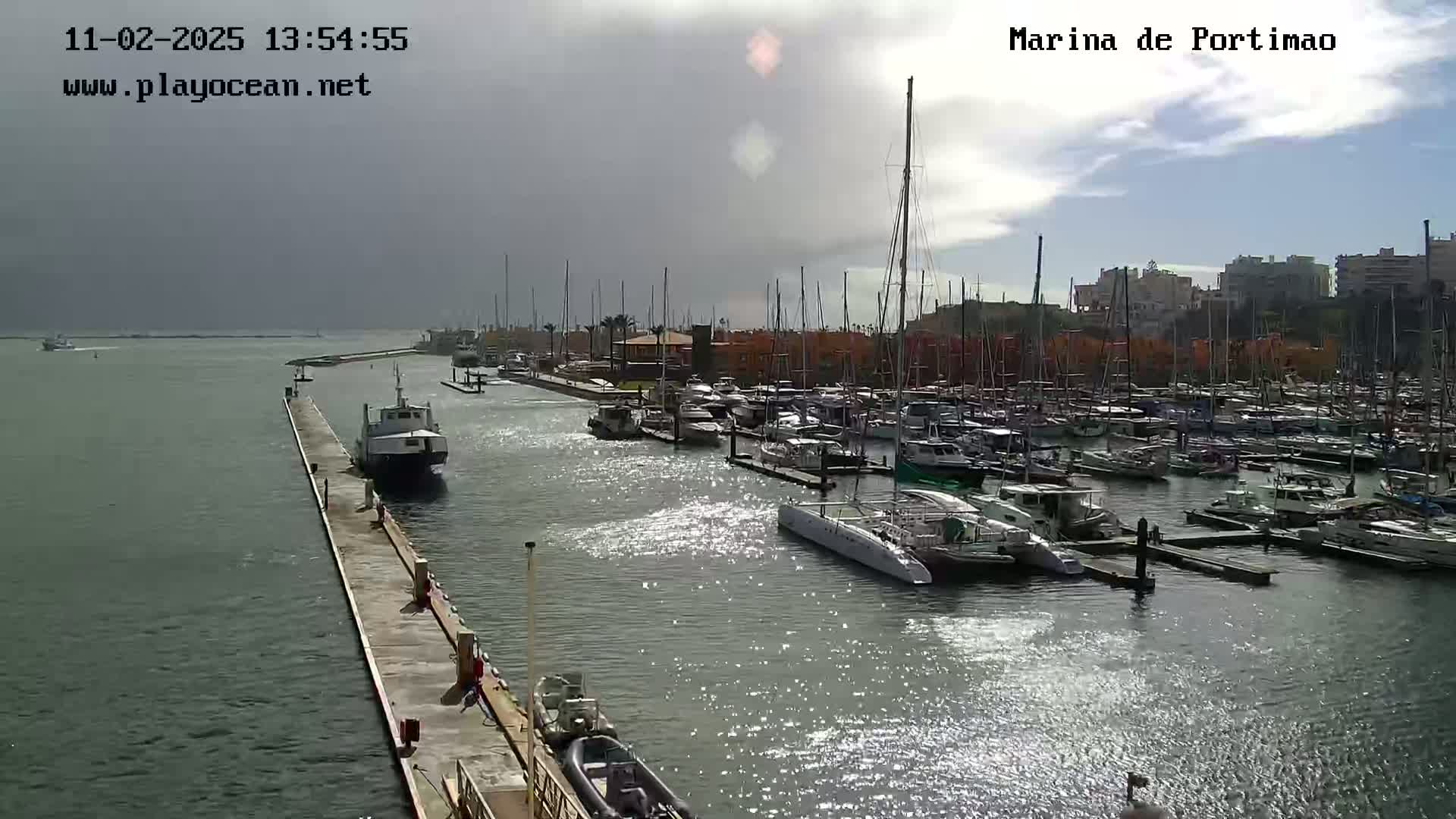 A marina filled with numerous boats and yachts on a partly cloudy day.