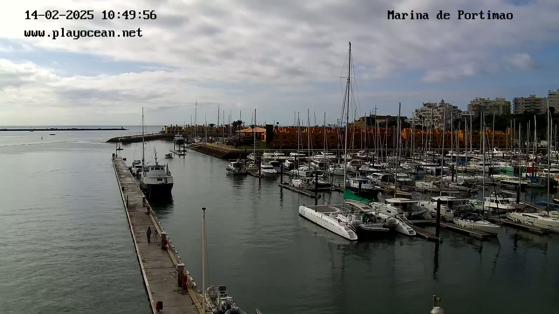 A marina filled with numerous boats and yachts on a partly cloudy day.