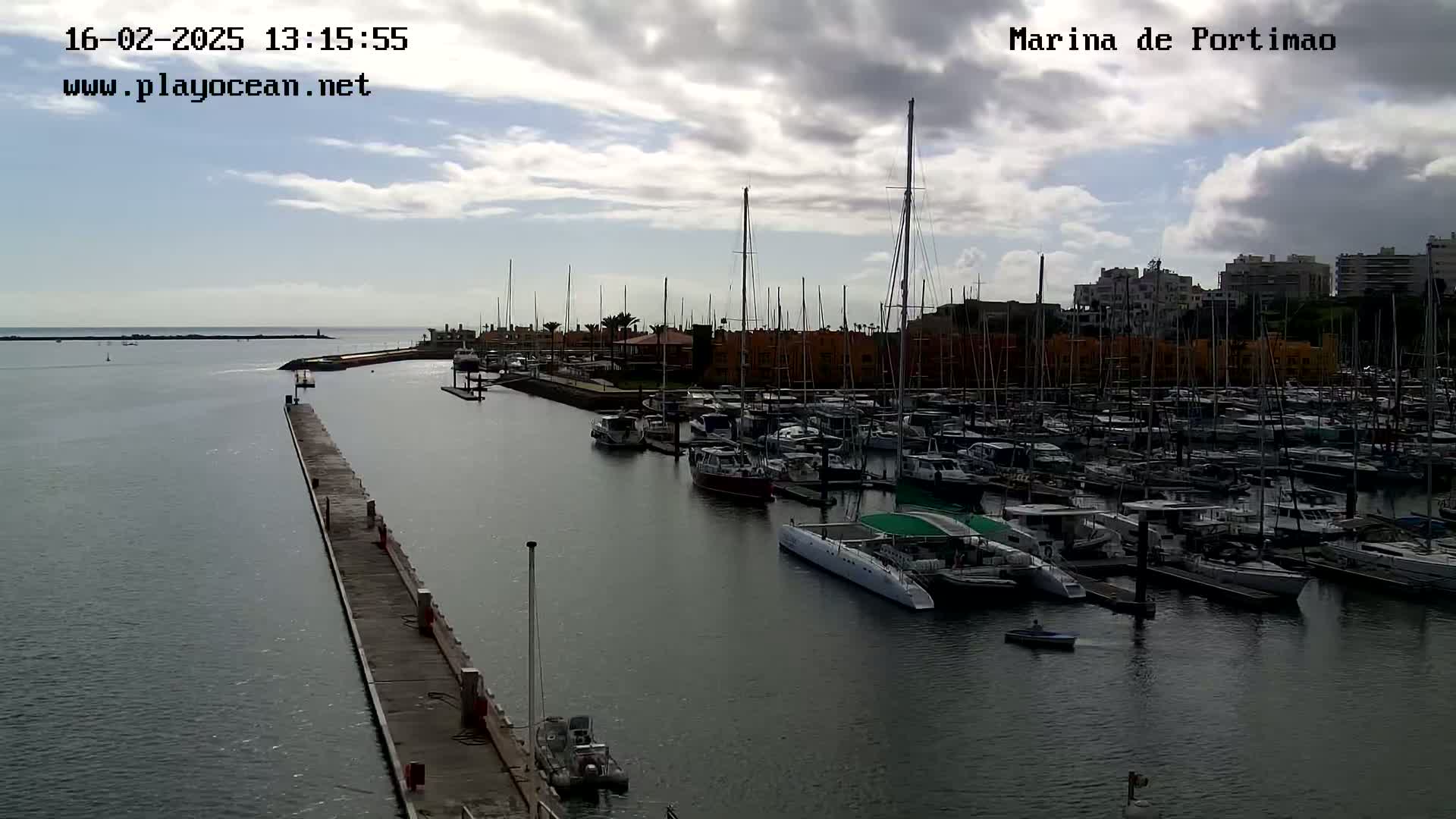 A marina filled with numerous boats and yachts under a partly cloudy sky.