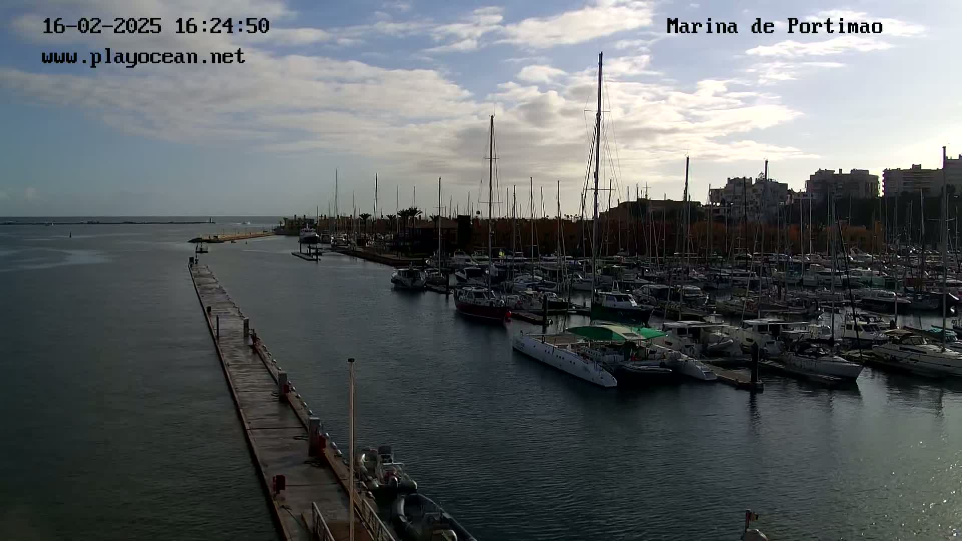 A marina filled with numerous boats and yachts under a partly cloudy sky.