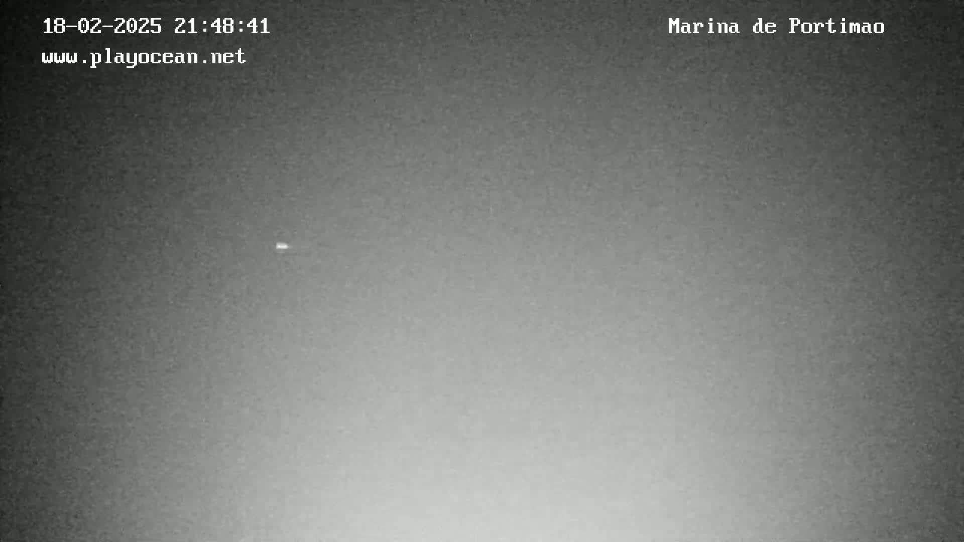 A nighttime, low-light image shows a mostly clear sky with a single, distant light source visible.