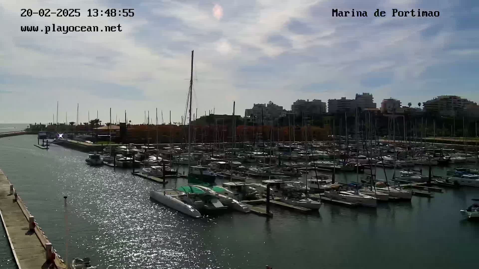 A marina filled with many sailboats and motorboats under a partly cloudy sky.
