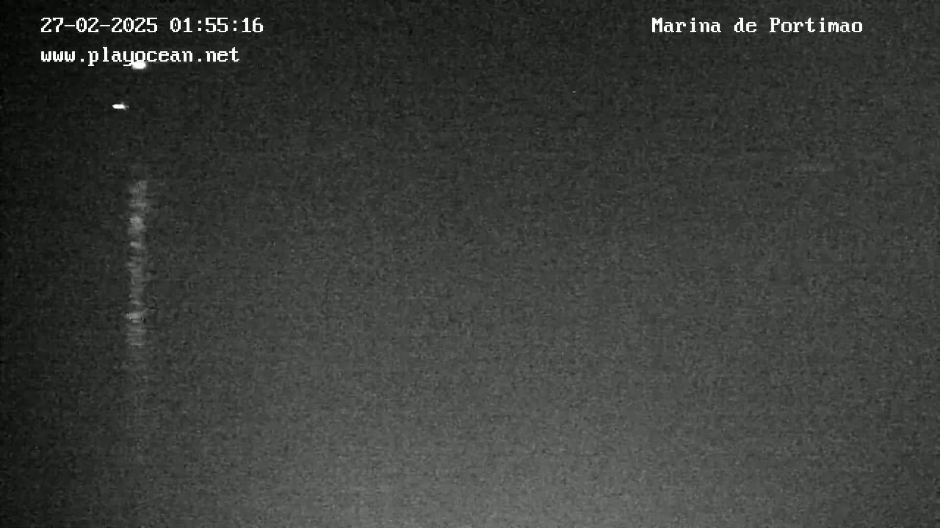 A nighttime, dark gray image shows a faint vertical light source in the center.