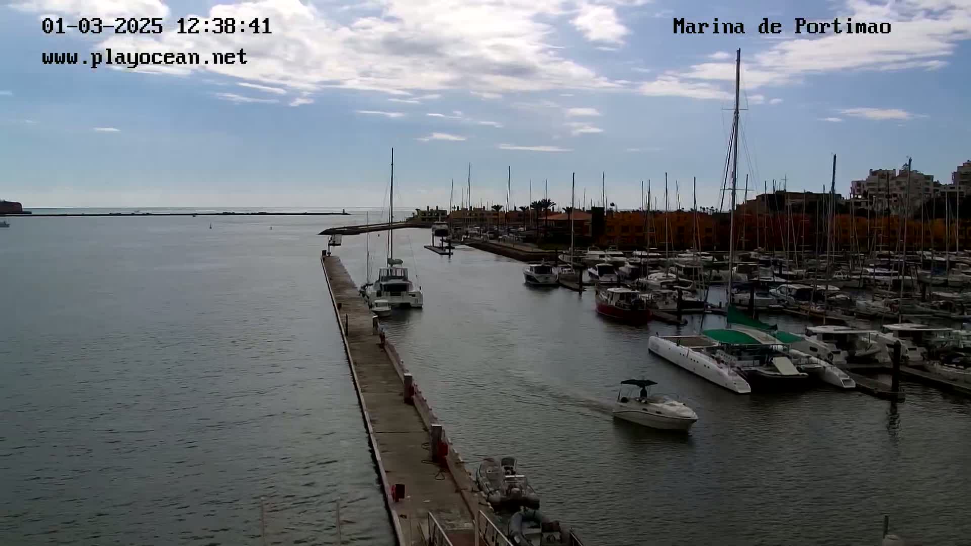 A marina filled with numerous boats and yachts under a partly cloudy sky.