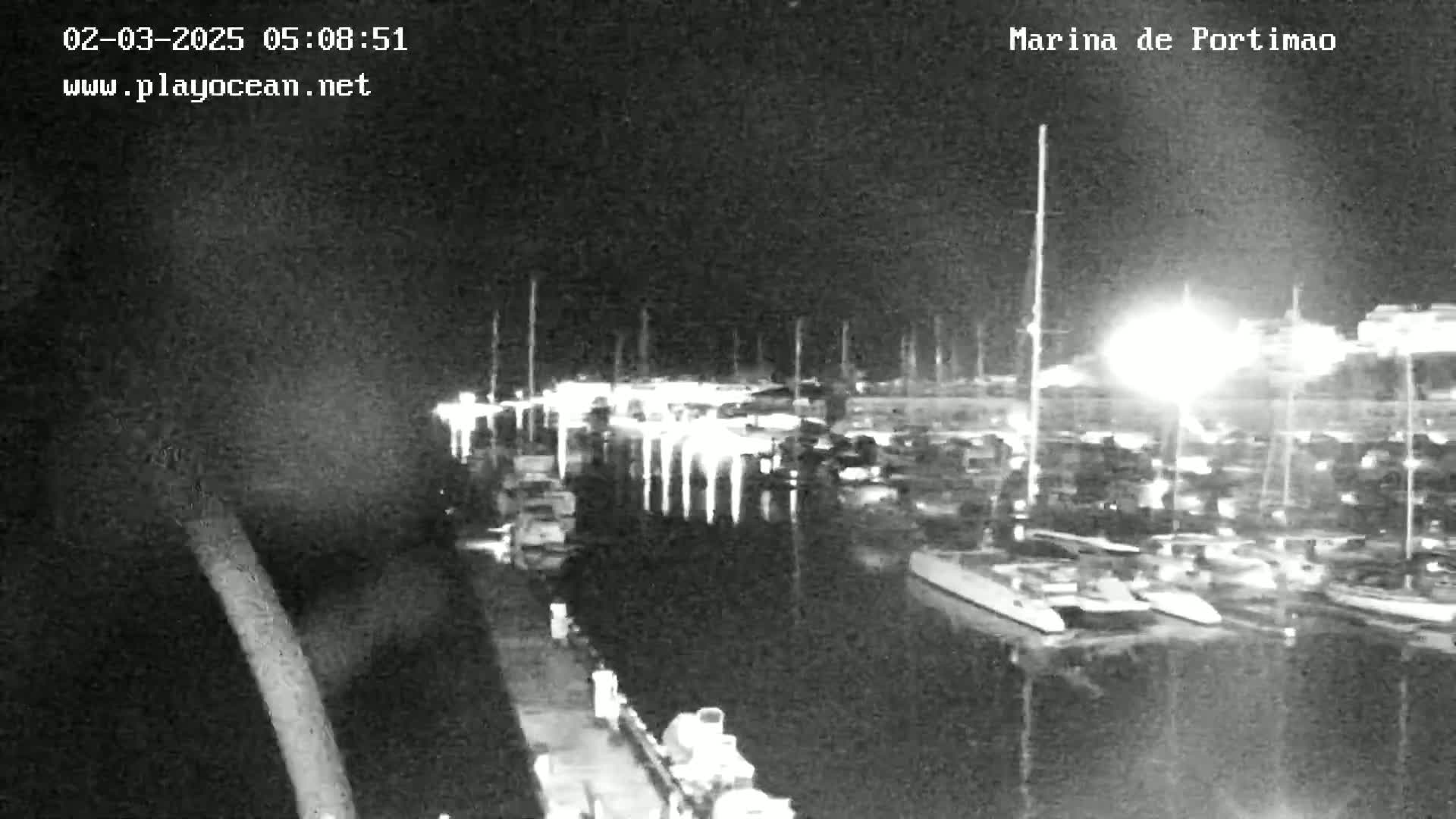 A nighttime, low-light image shows a marina filled with numerous boats docked along piers.