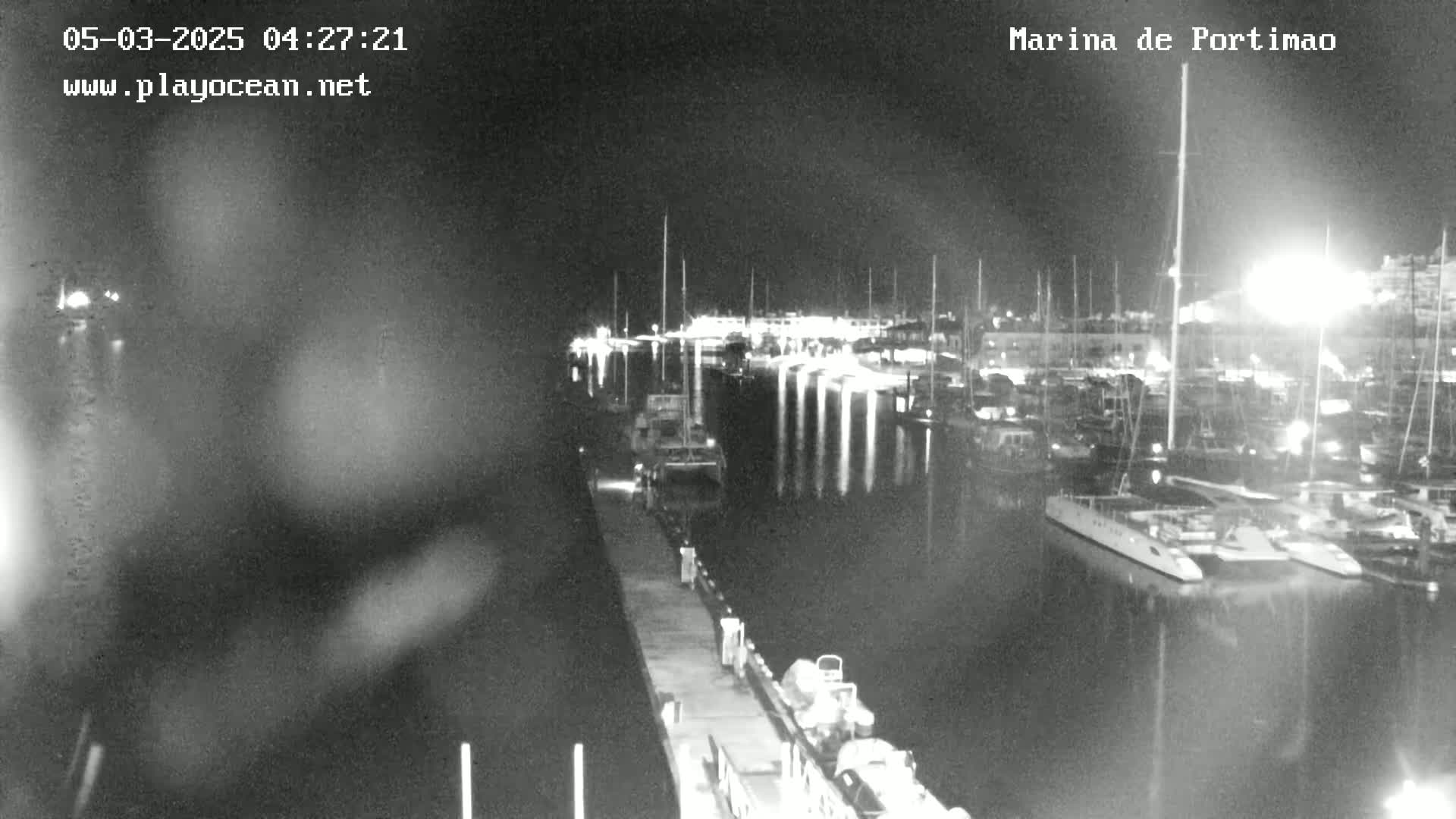 A nighttime, low-light view of a marina filled with docked boats and yachts.