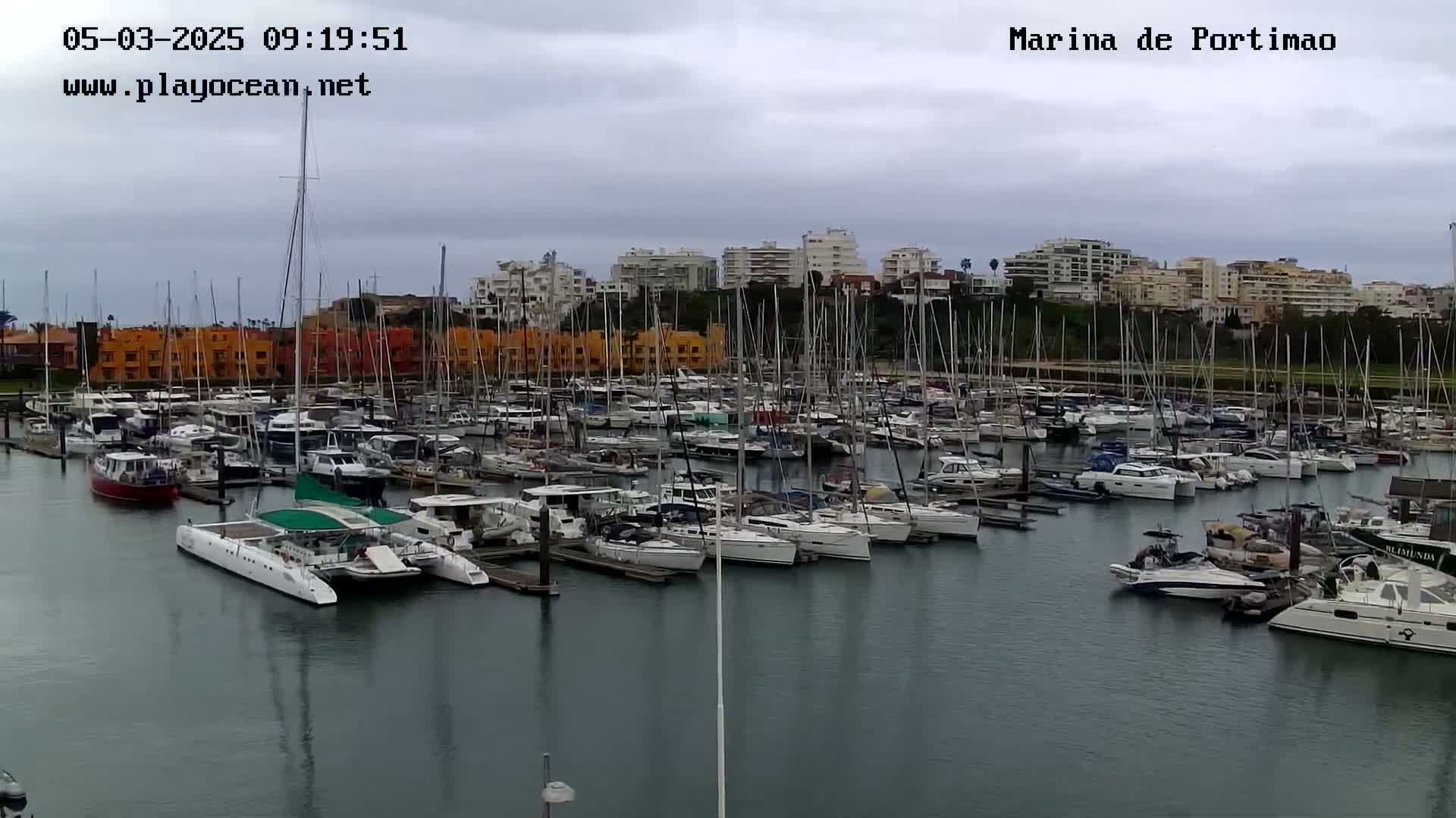 A marina filled with numerous boats and yachts under an overcast sky.