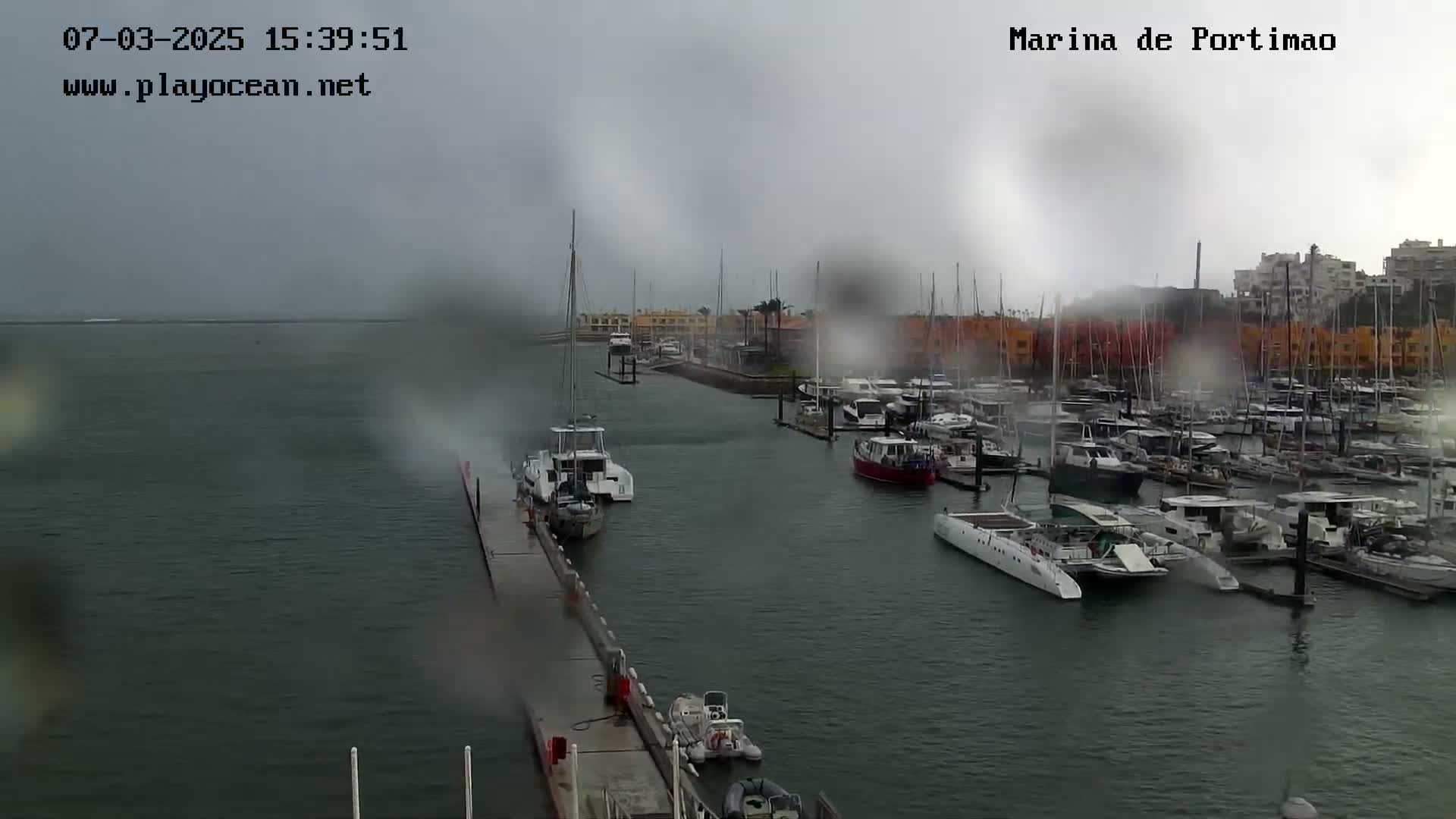 A marina filled with numerous boats is seen on a rainy day.