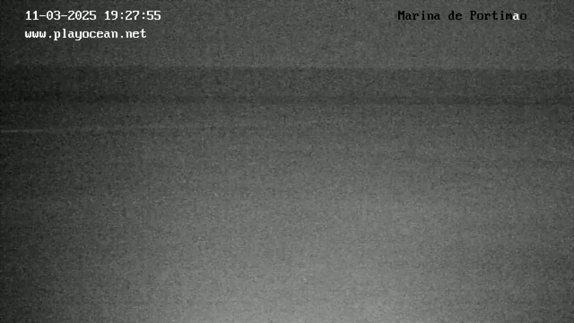 A low-light, grainy image shows a dark, possibly nighttime, view of a body of water.