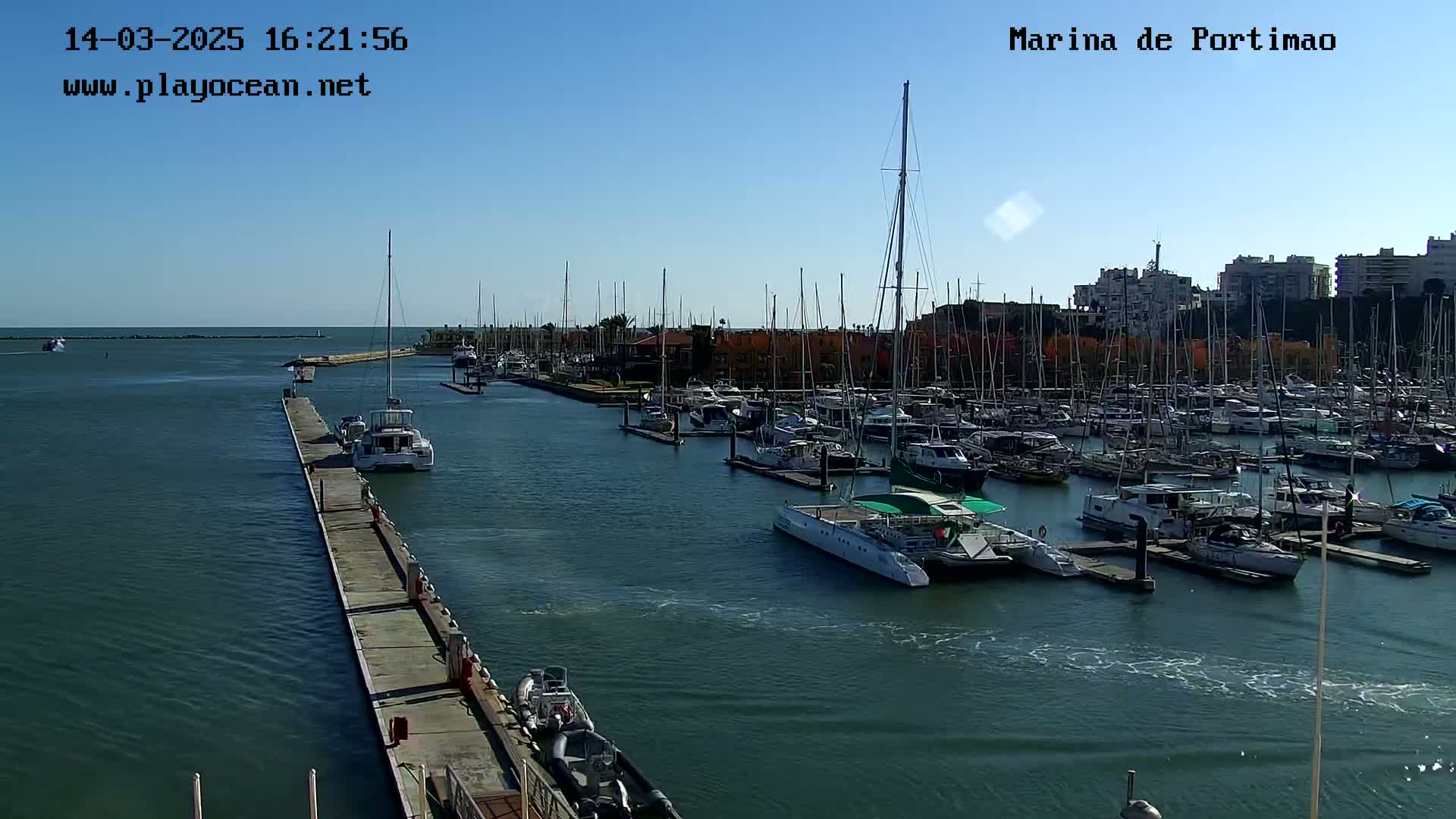 A marina filled with numerous sailboats and motorboats on a sunny day.