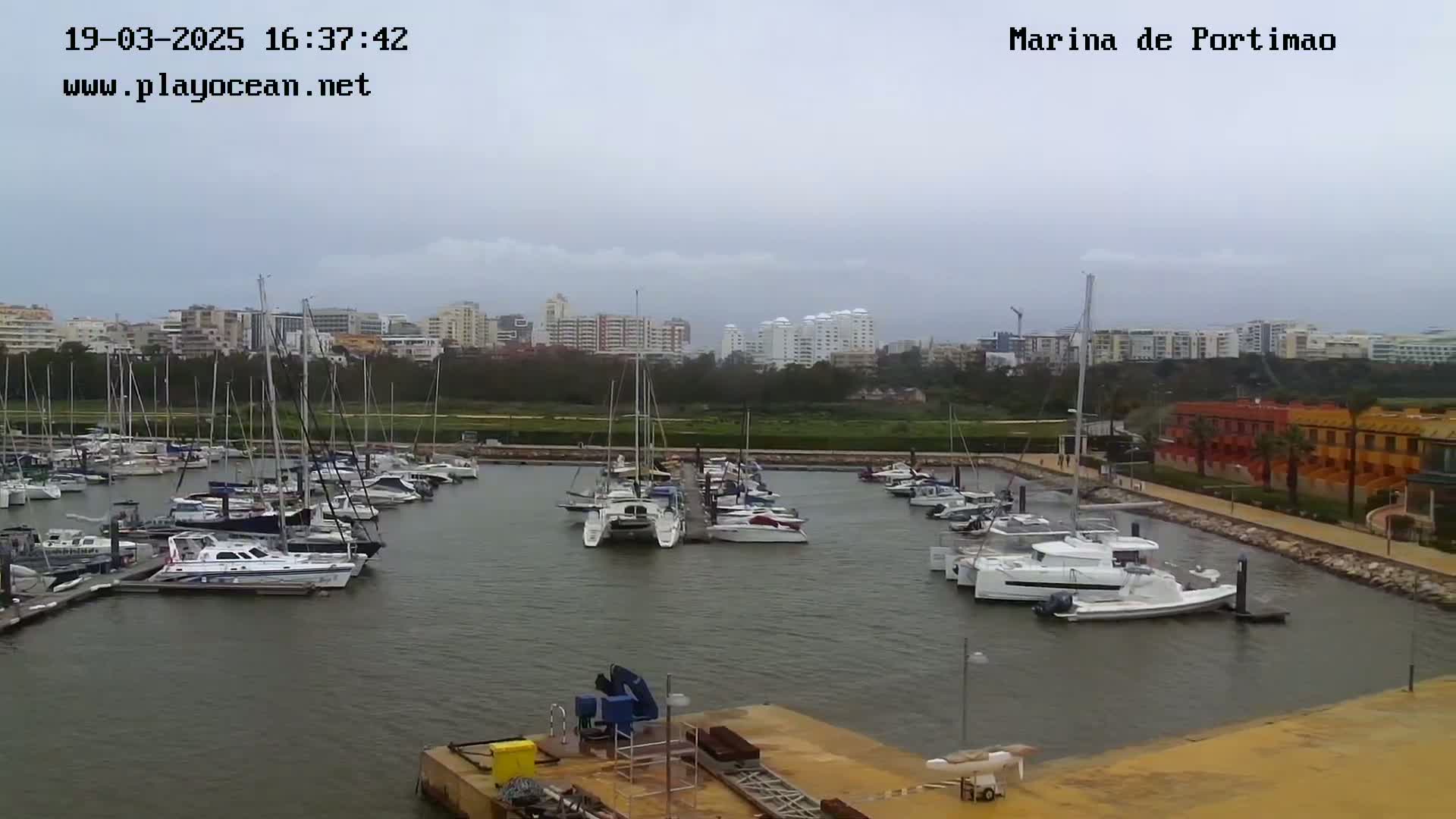 A marina filled with sailboats and motorboats is seen under an overcast sky.