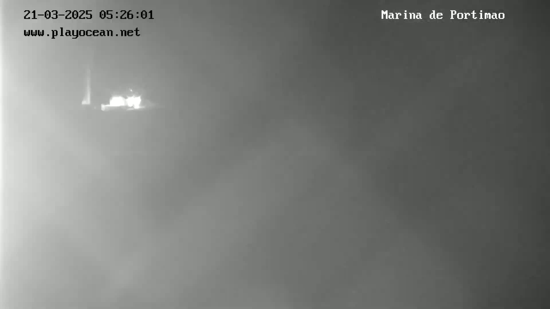 A dimly lit, foggy outdoor scene shows a blurry, indistinct object in the distance.