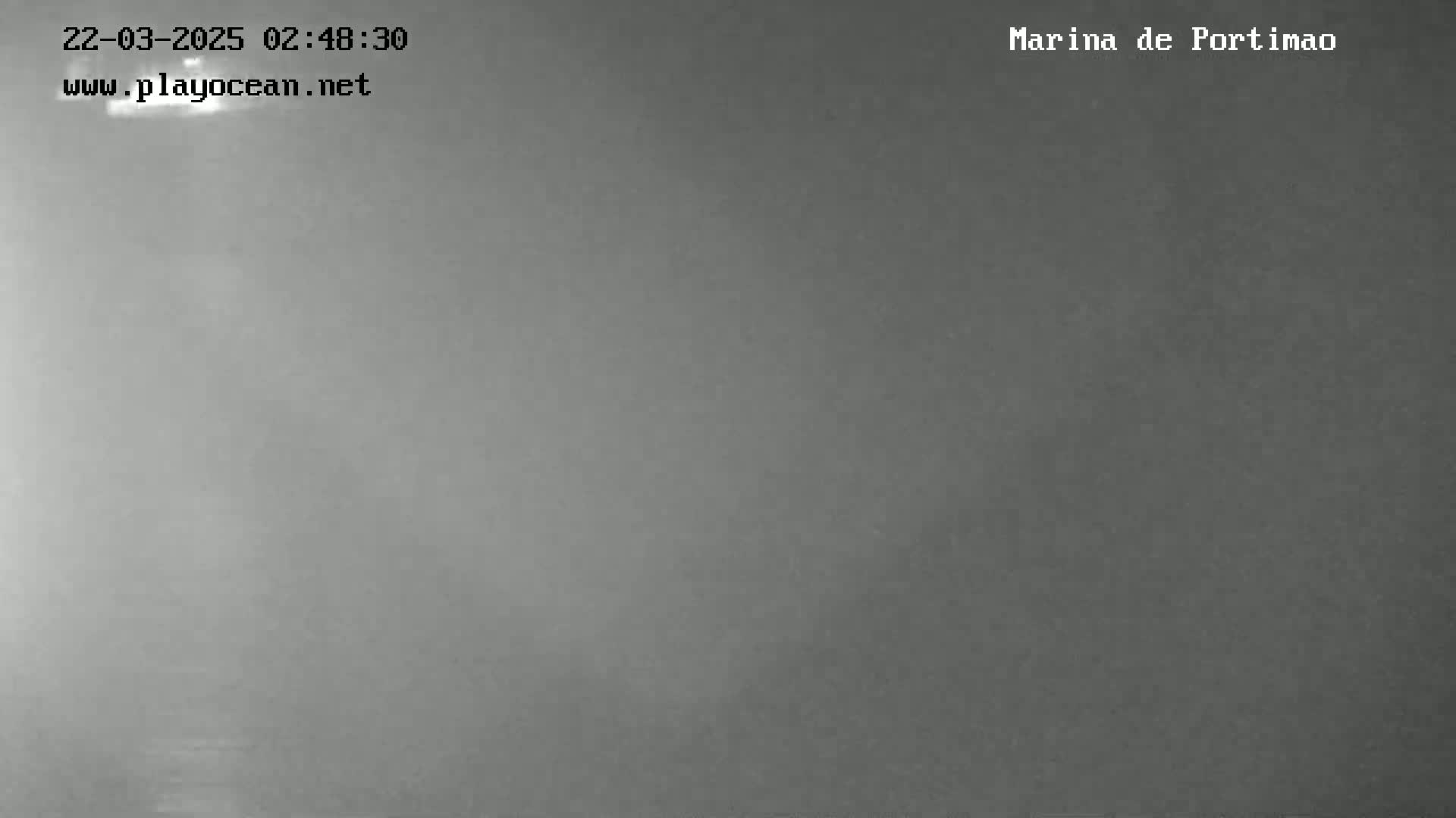 A dark, foggy or overcast scene shows a body of water, possibly at night.