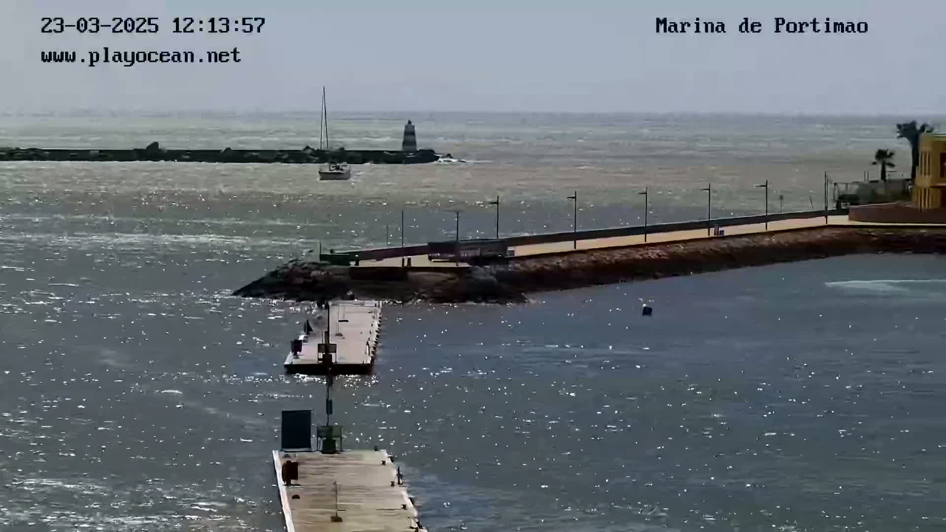 A marina with a long pier and calm, slightly choppy water under a mostly clear sky.