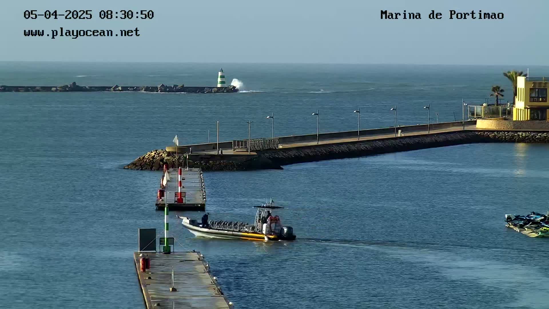 A marina with a boat leaving the harbor on a partly sunny day with some choppy water.
