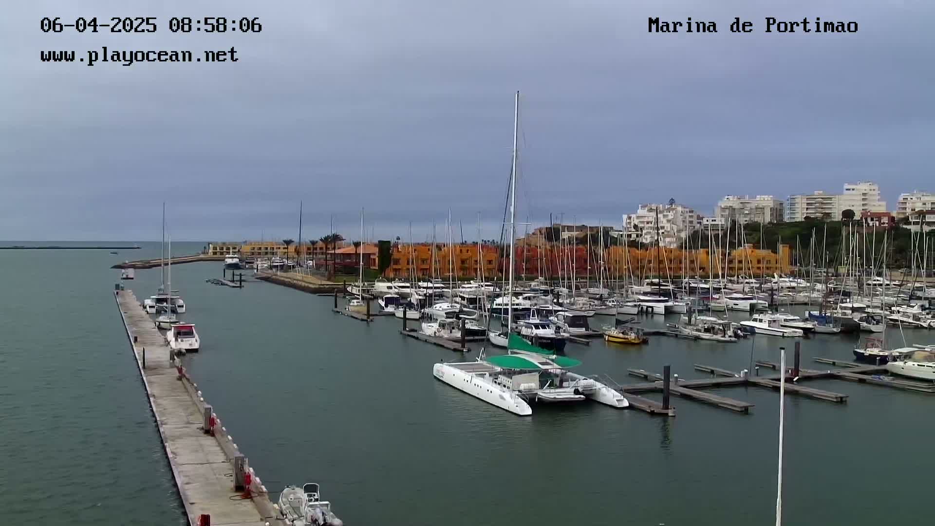 A marina filled with numerous sailboats and motorboats is seen on an overcast day.