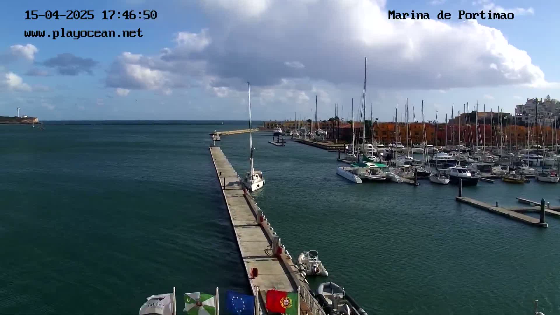 A marina filled with numerous boats and yachts under a partly cloudy sky.