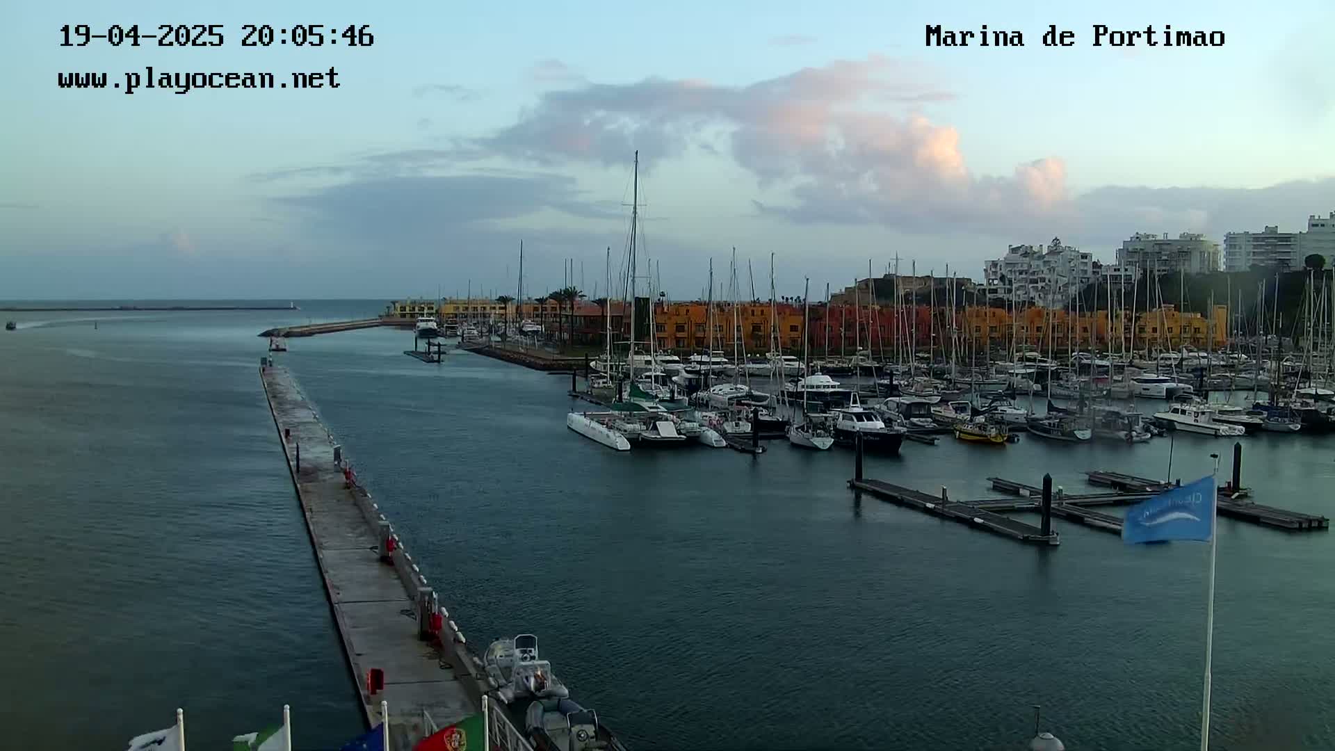 A marina filled with numerous boats and yachts under a partly cloudy sky.
