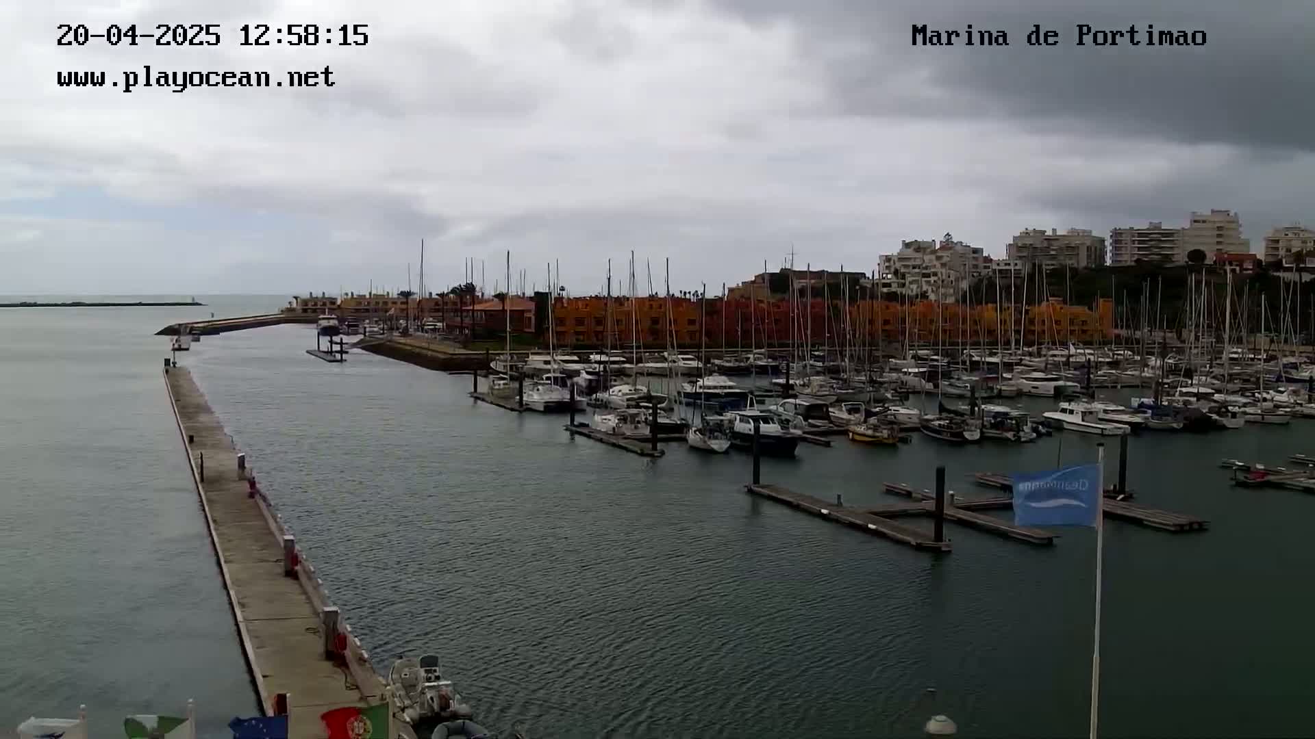 A marina filled with numerous boats is seen under an overcast sky.