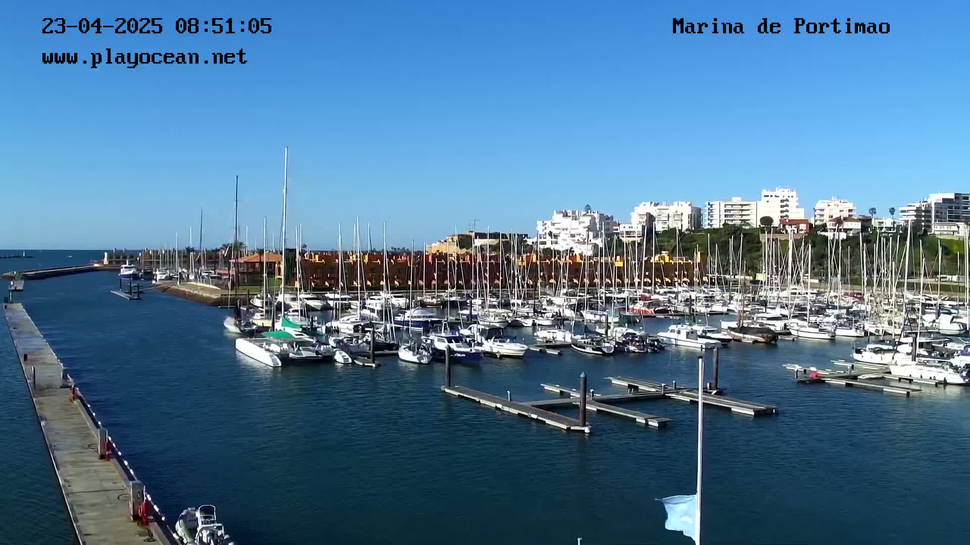 A marina filled with numerous sailboats and motorboats on a sunny day.